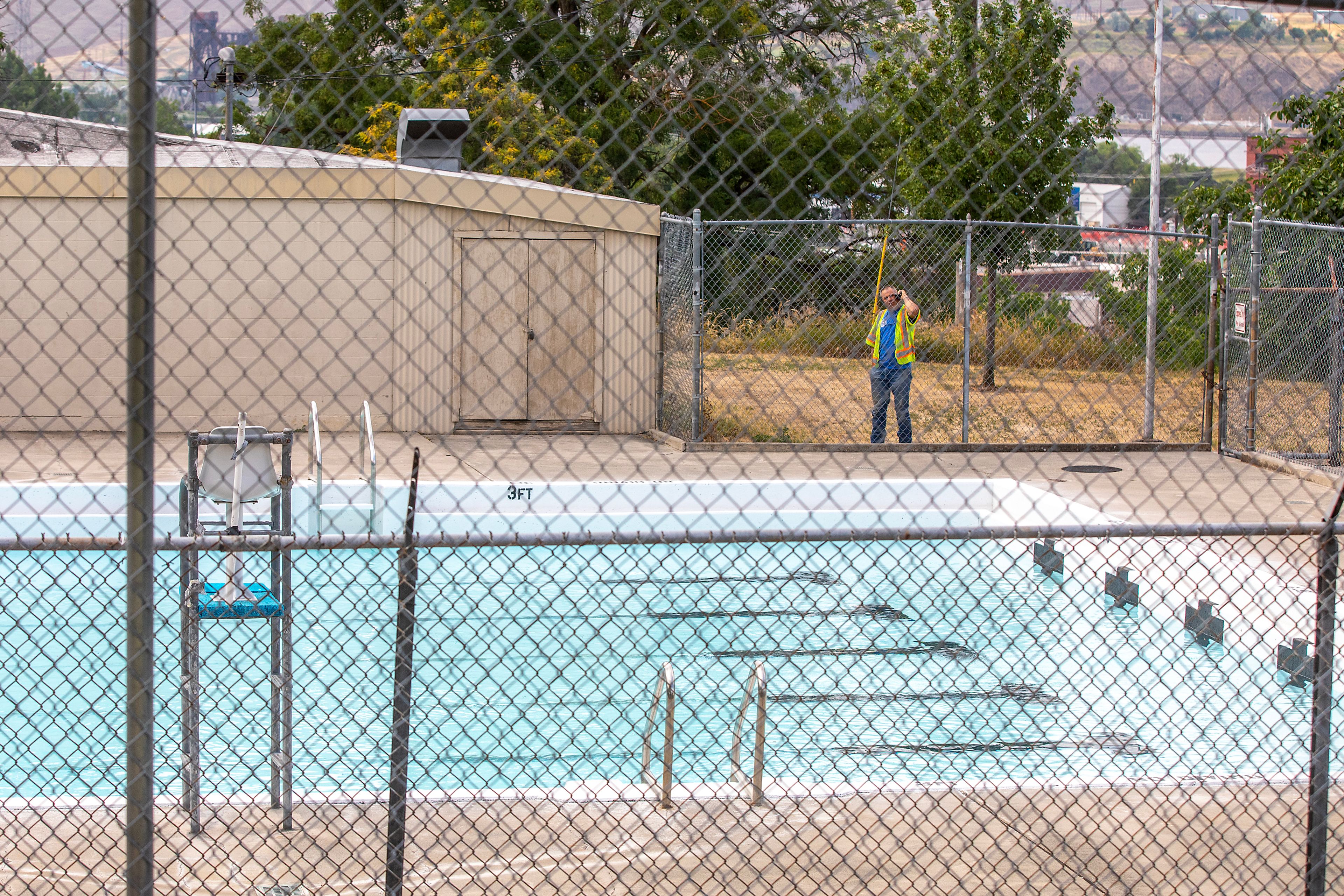 A worker looks on from outside the fence of the Bert Lipps Pool Thursday in Lewiston.