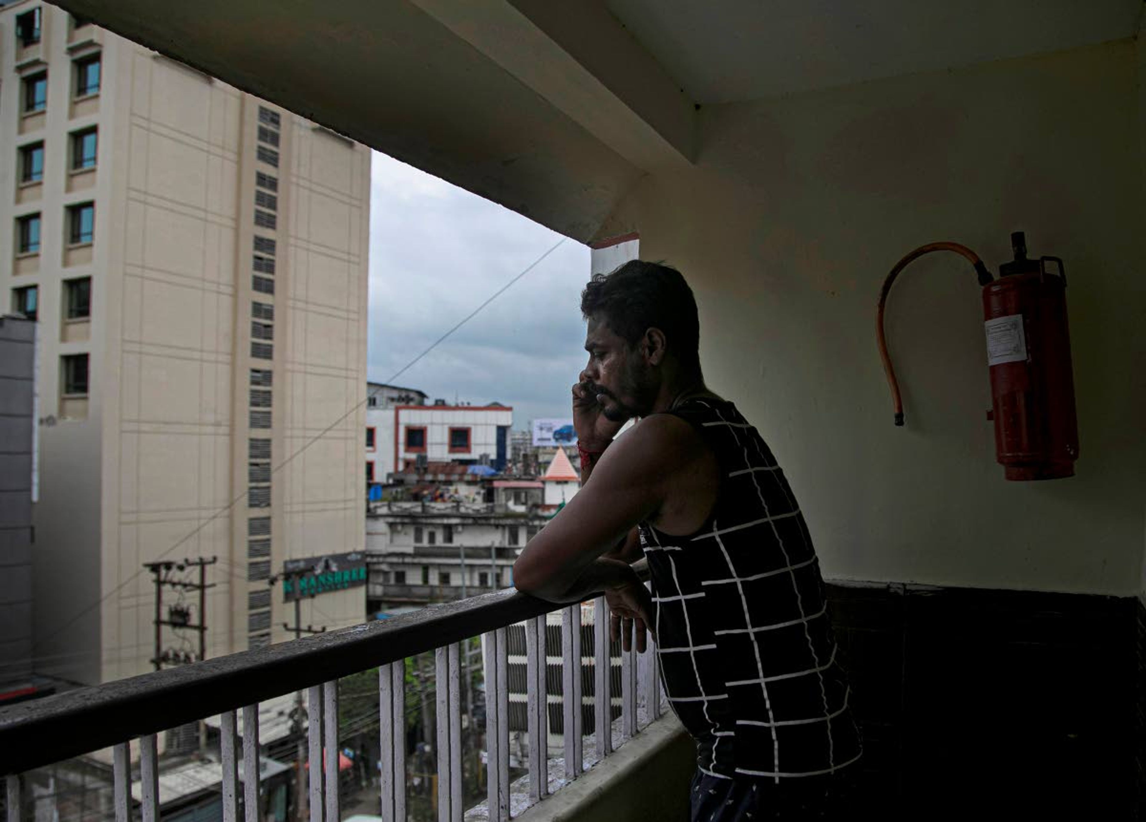 Ramananda Sarkar, 43, speaks to his wife from the balcony of his hotel before starting his day cremating bodies of COVID-19 victims in Gauhati, India, Tuesday, Sept. 15, 2020. Sarkar, who was deep in debt and desperate for money, took the job of lighting funeral pyres after failing to pay back a loan he'd taken to start selling sugarcane juice on a wooden cart. When his landlord heard about Sarkar's work, he told him he would have to move out. Thankfully a district official arranged a hotel room for him. Sarkar was also stopped from returning to his village to visit his family, first by the village head and then, after local authorities intervened on his behalf, by the villagers themselves. (AP Photo/Anupam Nath)