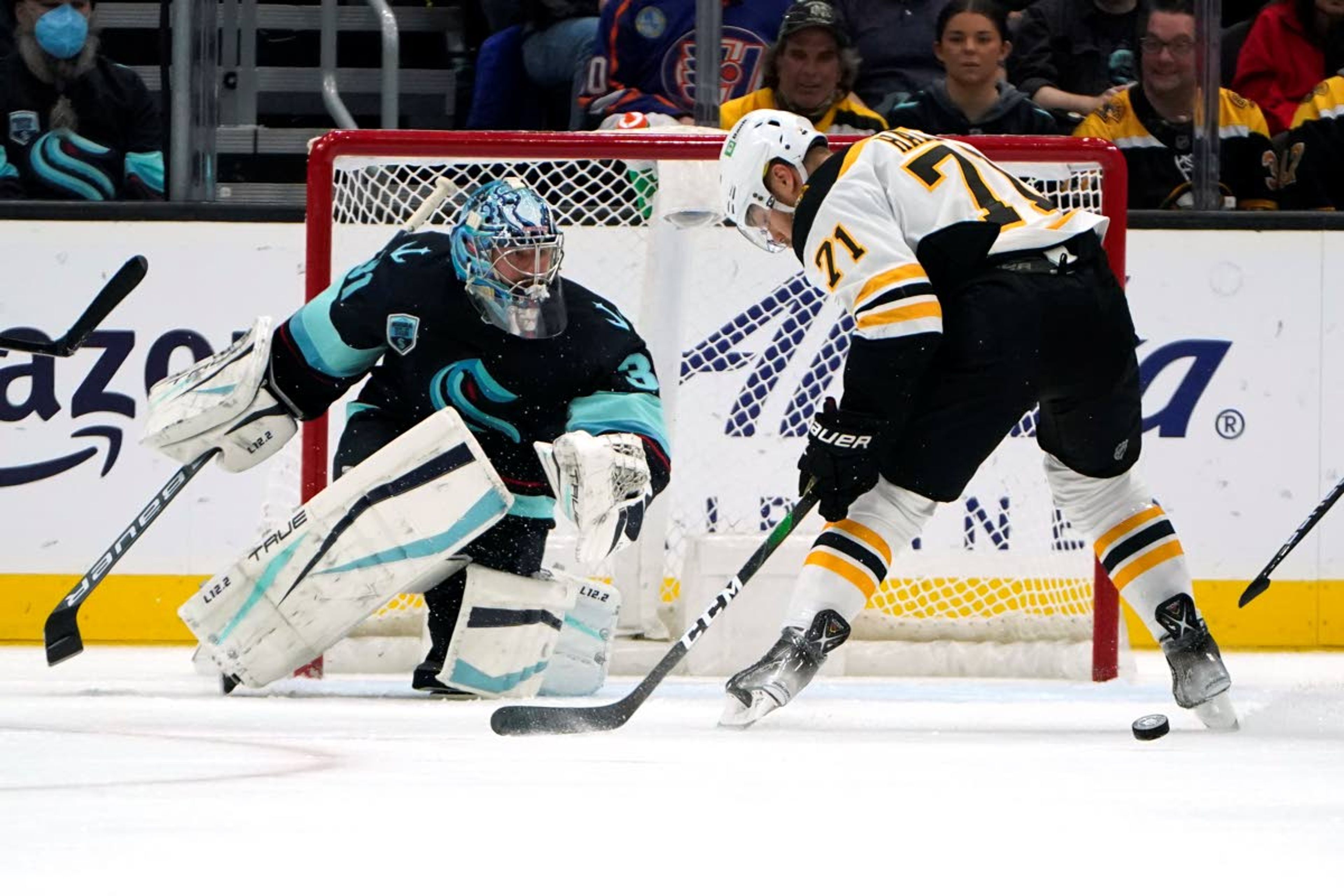 Seattle Kraken goaltender Philipp Grubauer, left, and Boston Bruins' Taylor Hall eye the puck during the second period of an NHL hockey game Thursday, Feb. 24, 2022, in Seattle. (AP Photo/Elaine Thompson)