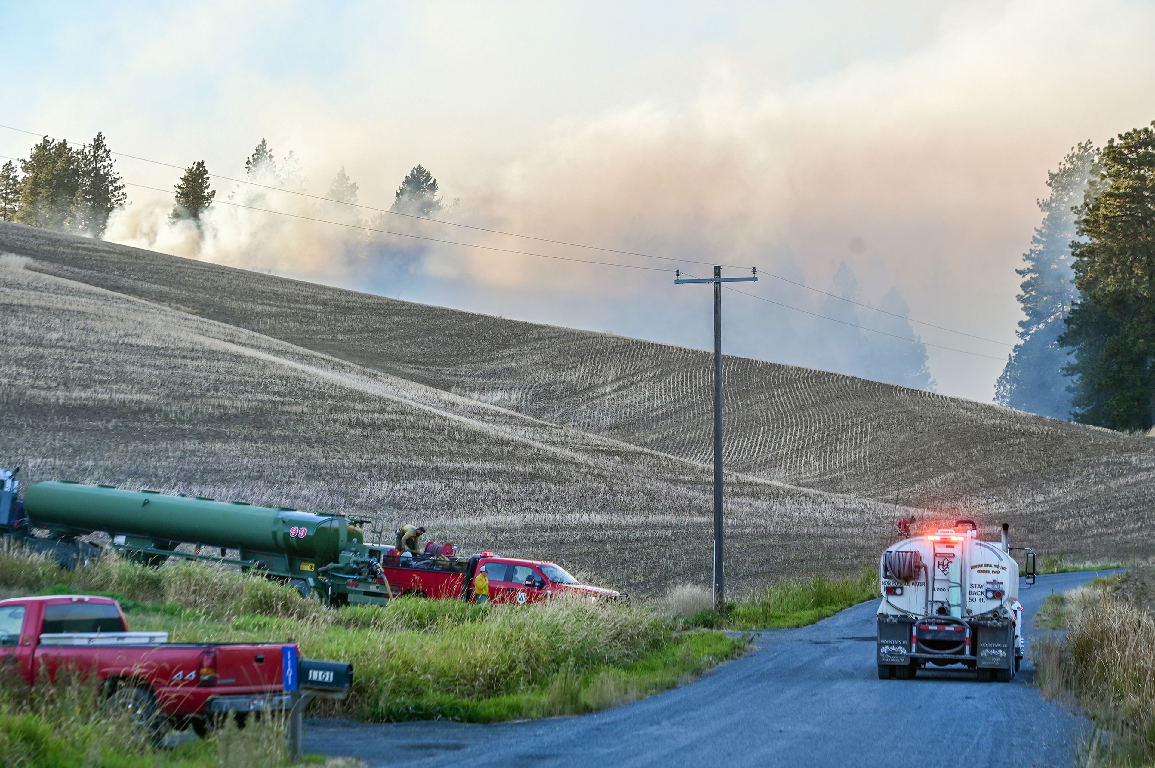 A fire truck attaches to a water tank Friday along Teare Road as smoke rises from the Wallen Fire in Moscow.