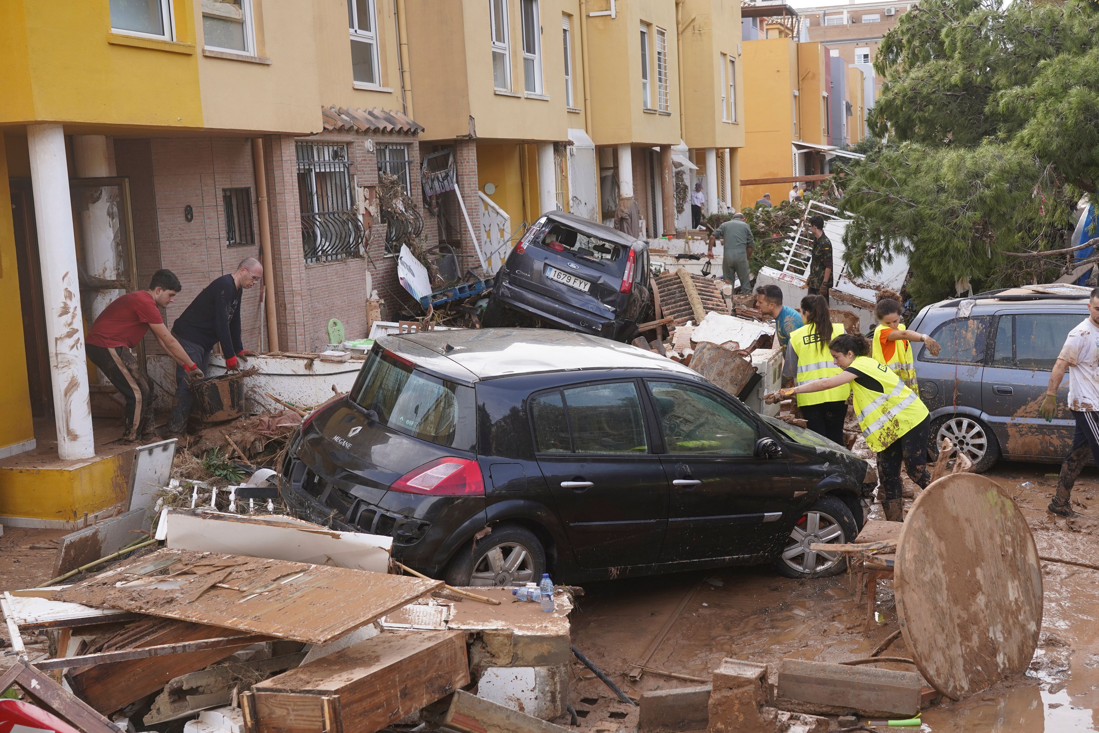 People clear debris from the street after floods in Massanassa, just outside of Valencia, Spain, Friday, Nov. 1, 2024. (AP Photo/Alberto Saiz)