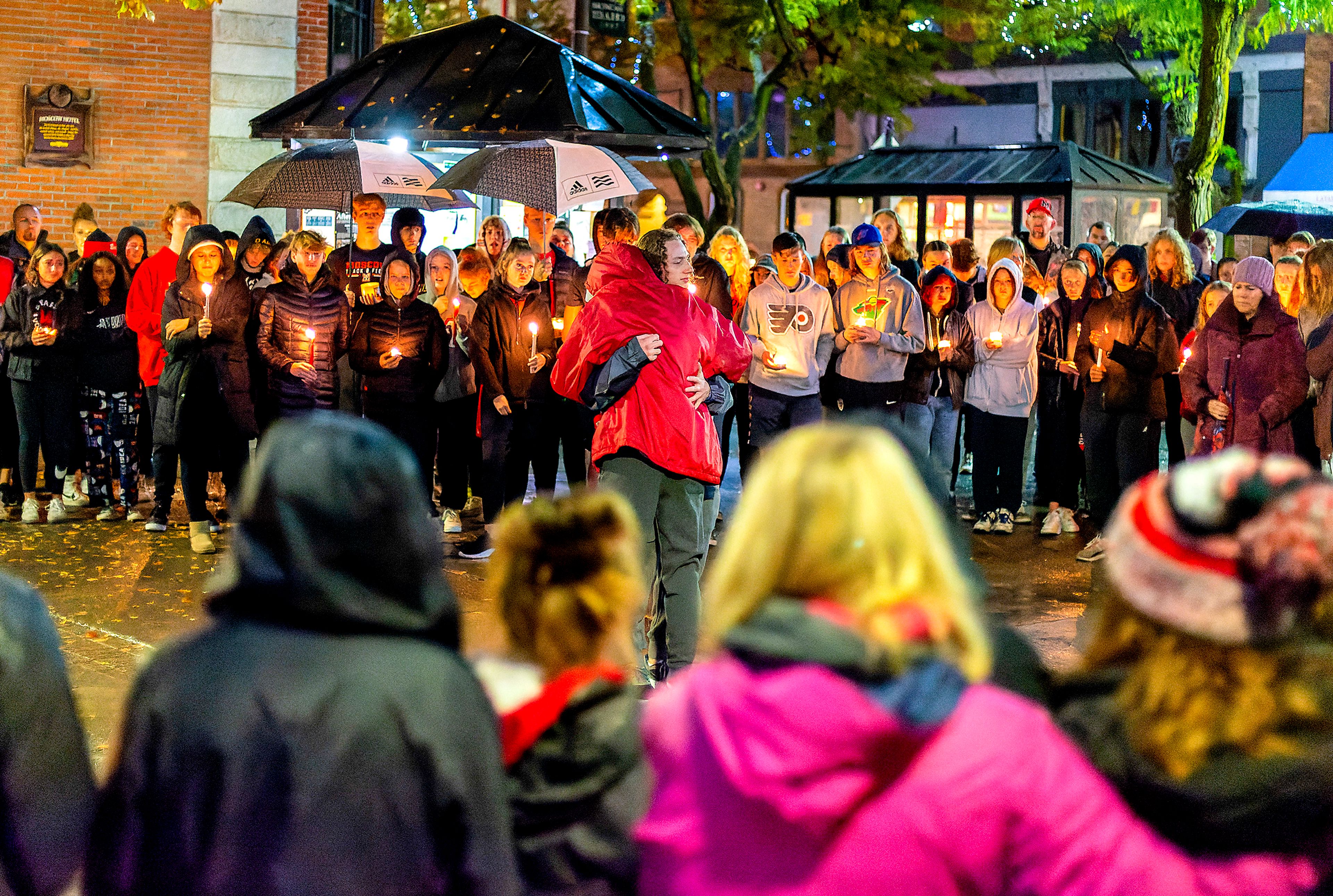 Members of Lance Abendroth’s family hug each other during a candlelight vigil in his honor Thursday. Abendroth, 51, died after a long battle with cancer.