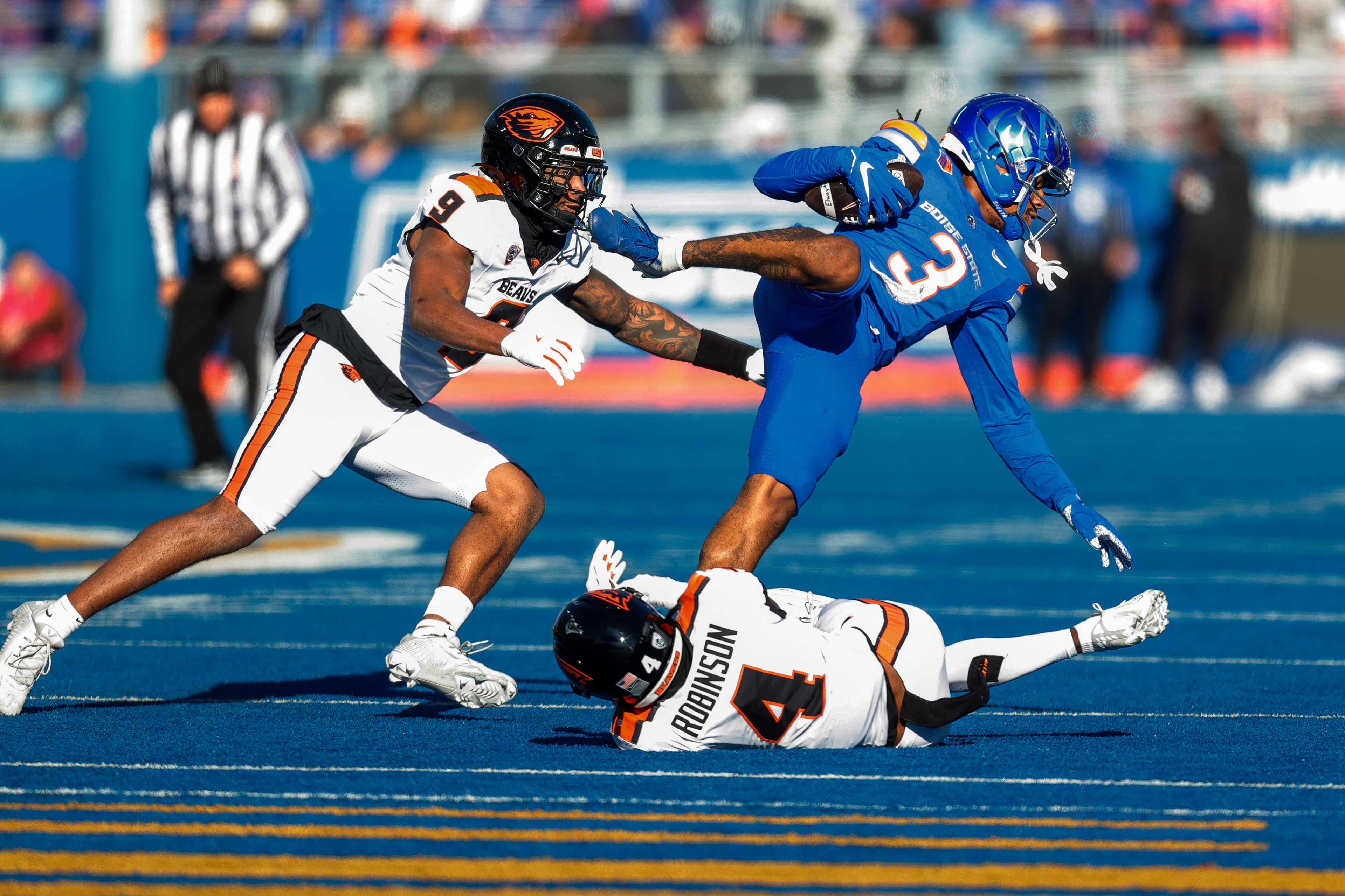 Boise State wide receiver Latrell Caples (3) is tripped up on after a reception by Oregon State defensive back Jaden Robinson (4) and linebacker Isaiah Chisom (9) in the first half of an NCAA college football game, Friday, Nov. 29, 2024, in Boise, Idaho. (AP Photo/Steve Conner)