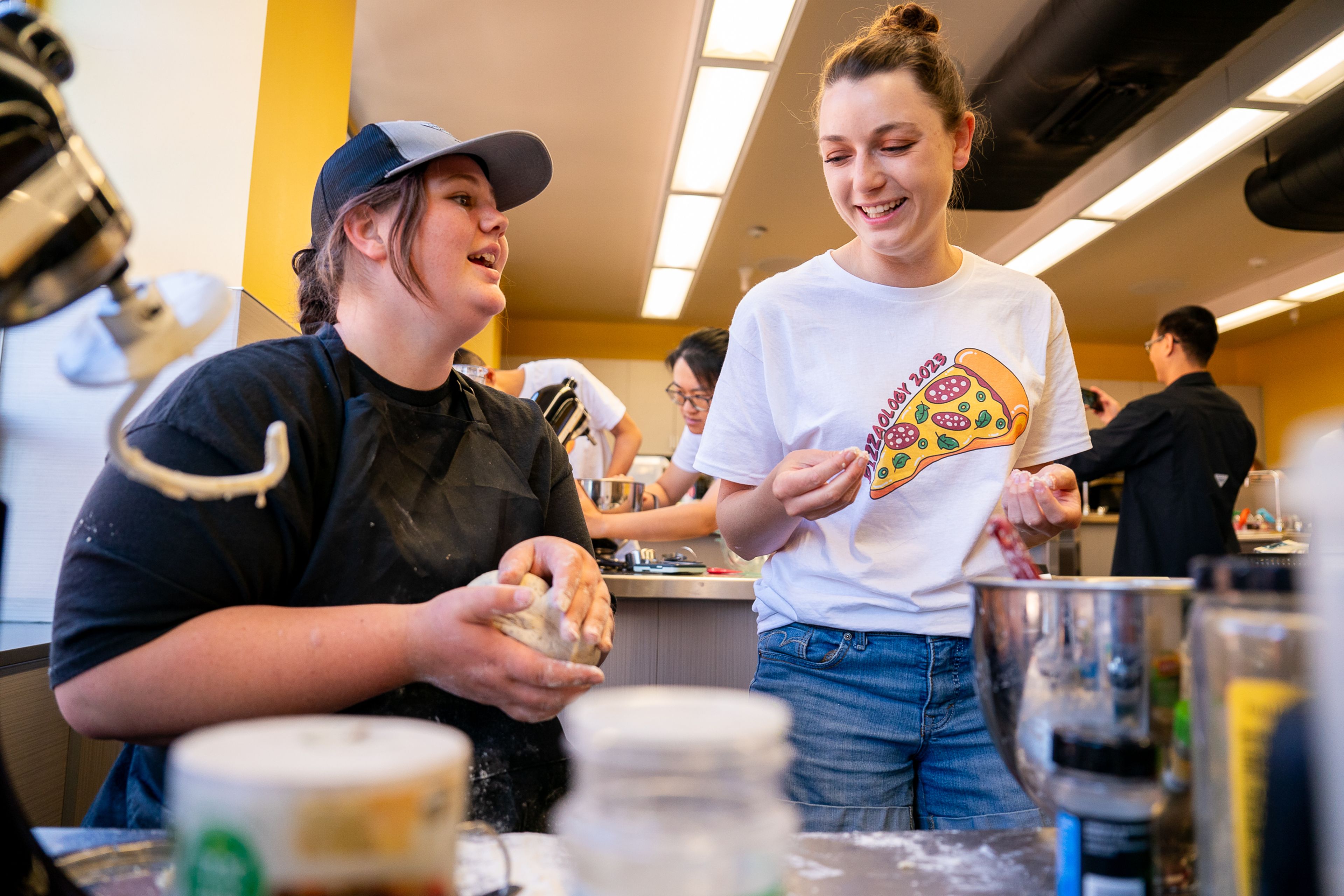 Skyler Cochrane, left, 17, of Chambers Flat, talks with instructor Belinda Sell about her dough during the final day of the 2023 Pizza-ology Camp on Wednesday at the Carmelita Spencer Food Laboratory in Moscow.