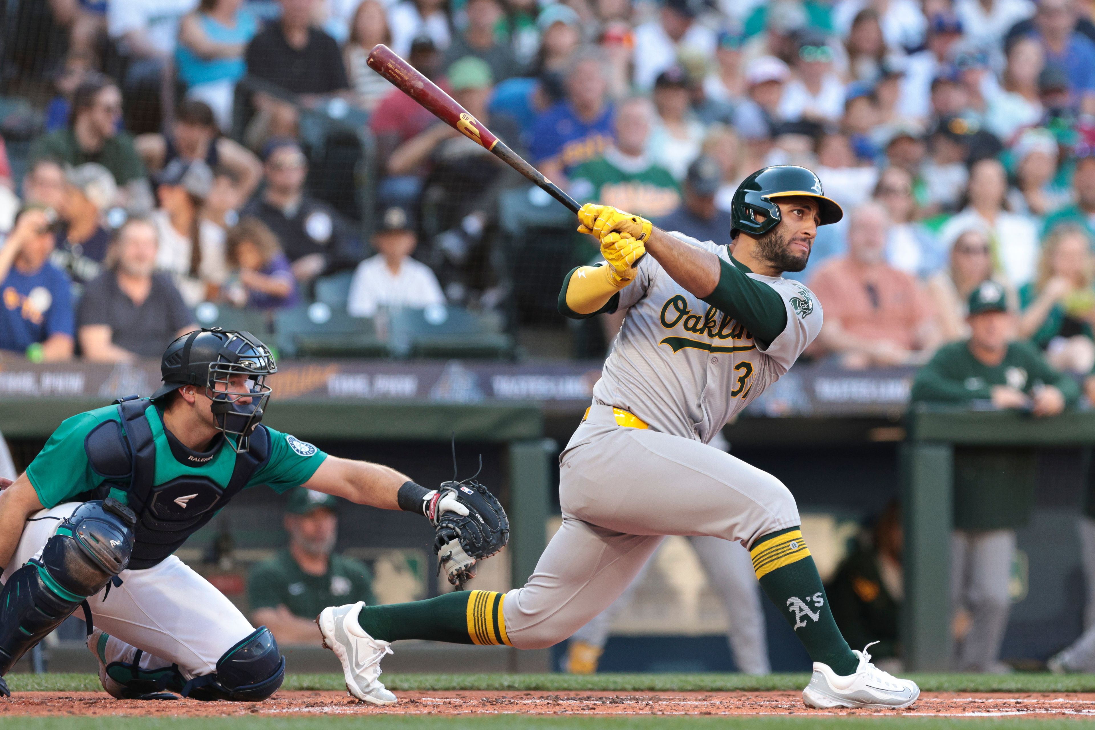 The Athletics' Abraham Toro watches his RBI single next to Mariners catcher Cal Raleigh during the third inning of a game Saturday, May 11, 2024, in Seattle.