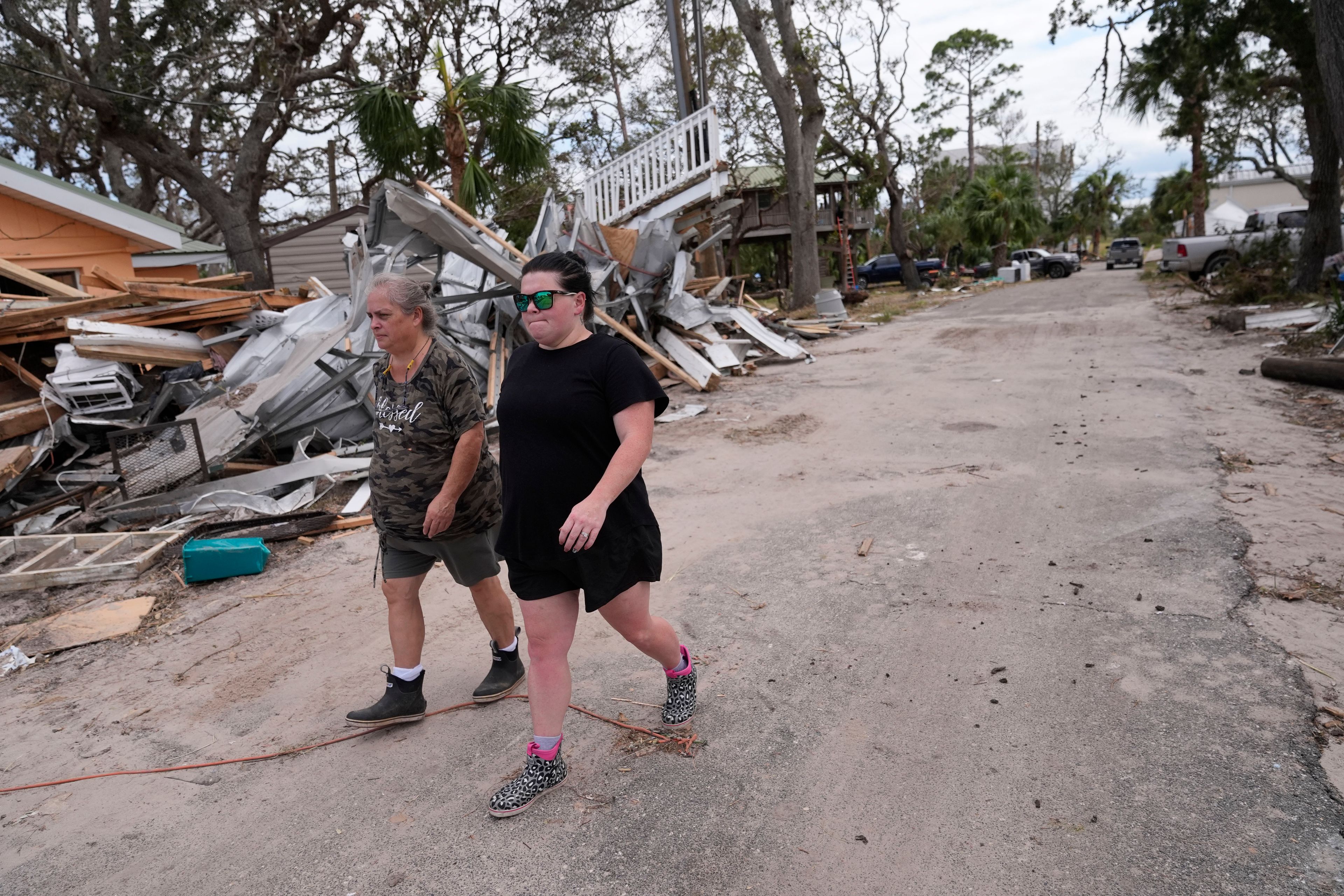 Charlene Huggins, and her daughter-in-law, Katelyn Huggins, right, walk past the destruction on their street in the aftermath of Hurricane Helene, in Horseshoe Beach, Fla., Saturday, Sept. 28, 2024. (AP Photo/Gerald Herbert)