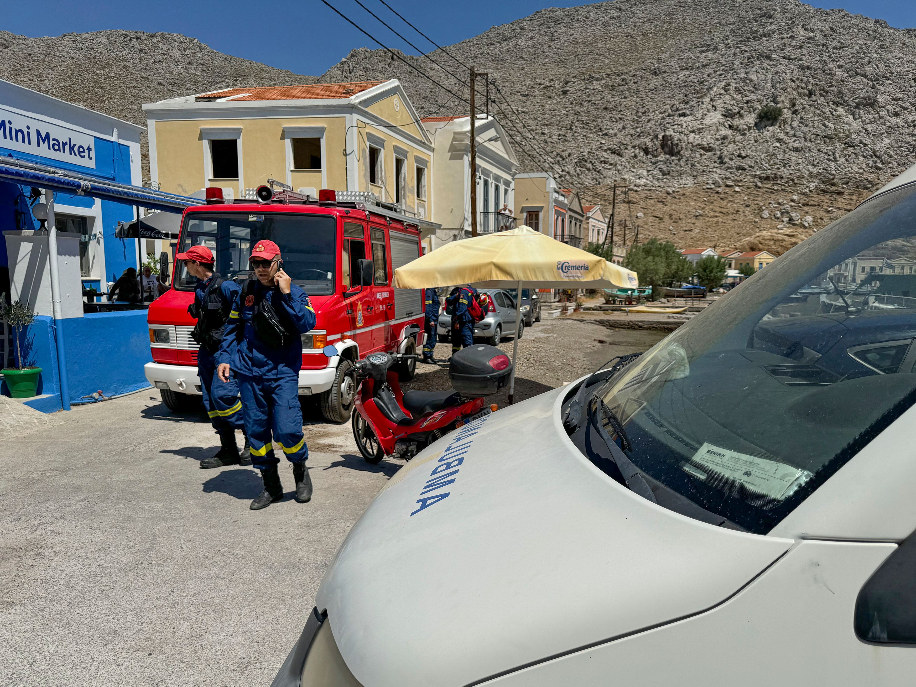 Greek Fire brigade personnel walk on a beachfront of Symi island, Greece Sunday, June 9, 2024. Police said that a body believed to be that of missing British TV presenter Michael Mosley was found on a Greek island Sunday morning.