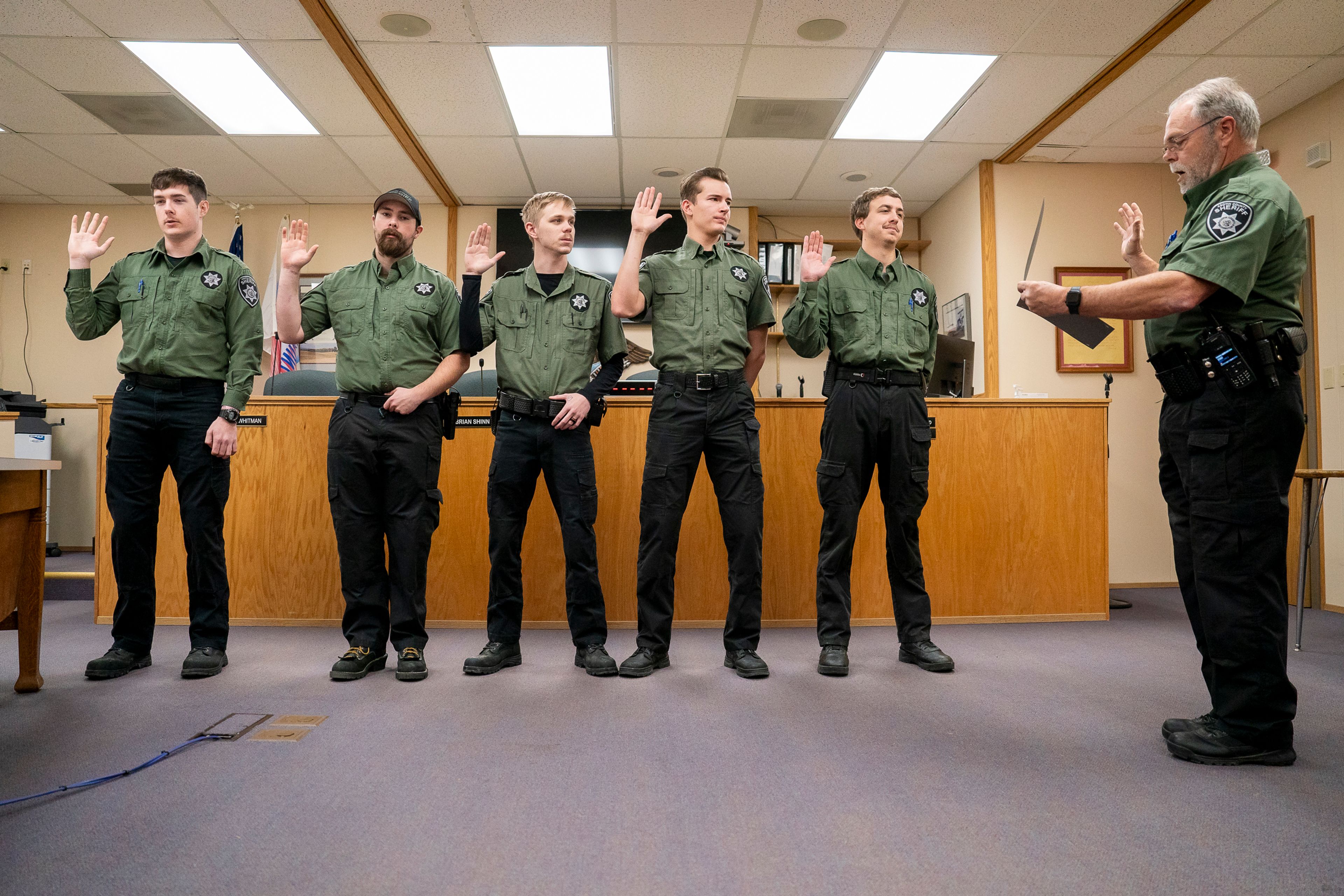 From left: Hunter Holloway, Michael Webster, Kayden Carpenter, Alex Hamm and Cody Moosman recite an oath read by Asotin County Sheriff John Hilderbrand, right, as they are sworn in as new corrections deputies on Thursday afternoon inside the Asotin County Courthouse Annex.