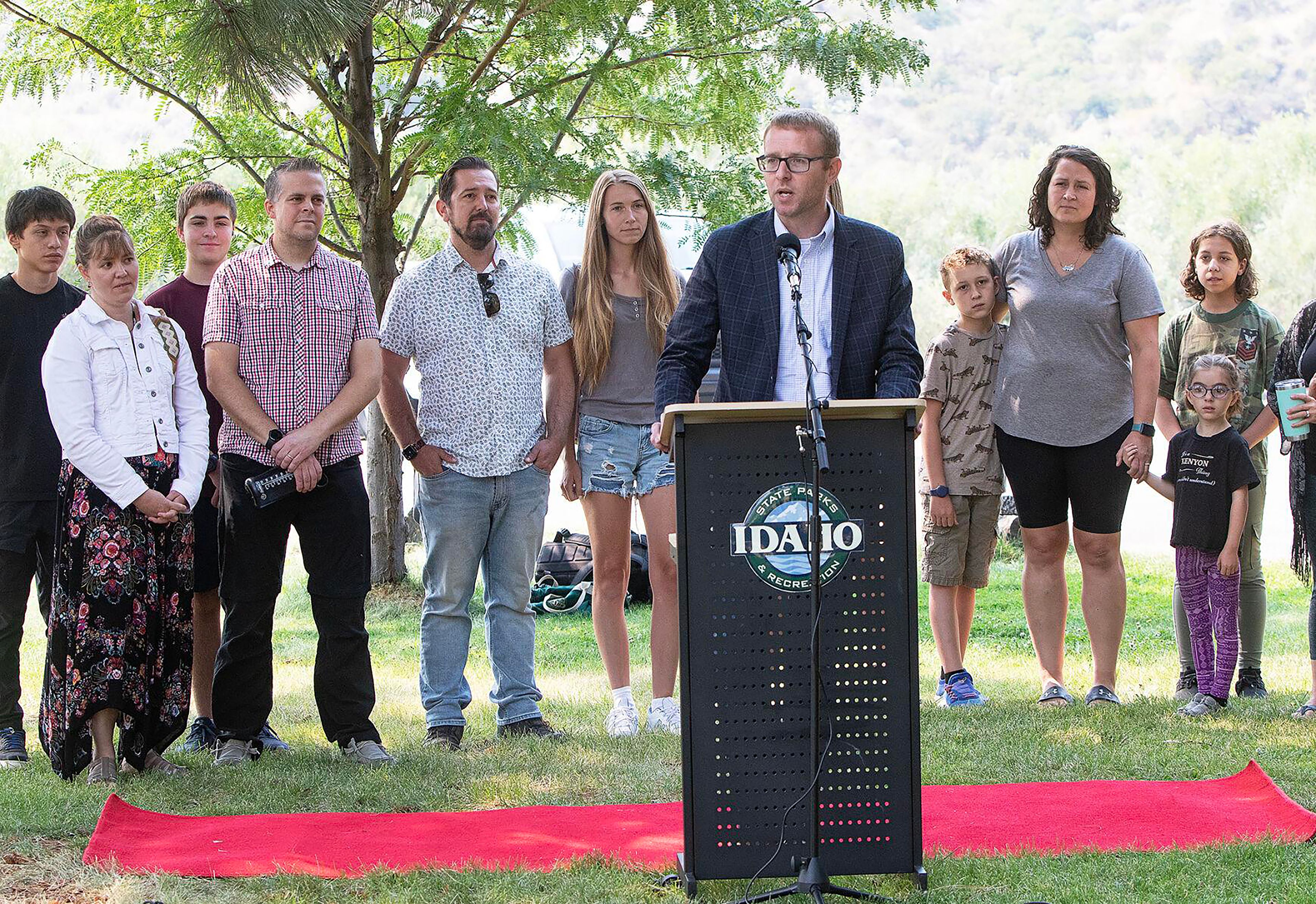 Idaho Department Health and Welfare Director Alex Adams speaks Wednesday during an event announcing the creation of the Idaho State Park Foster Family Passport program, with current Idaho foster families seen standing behind him. The program will provide foster families with free annual park passes granting access to all 30 Idaho state parks.