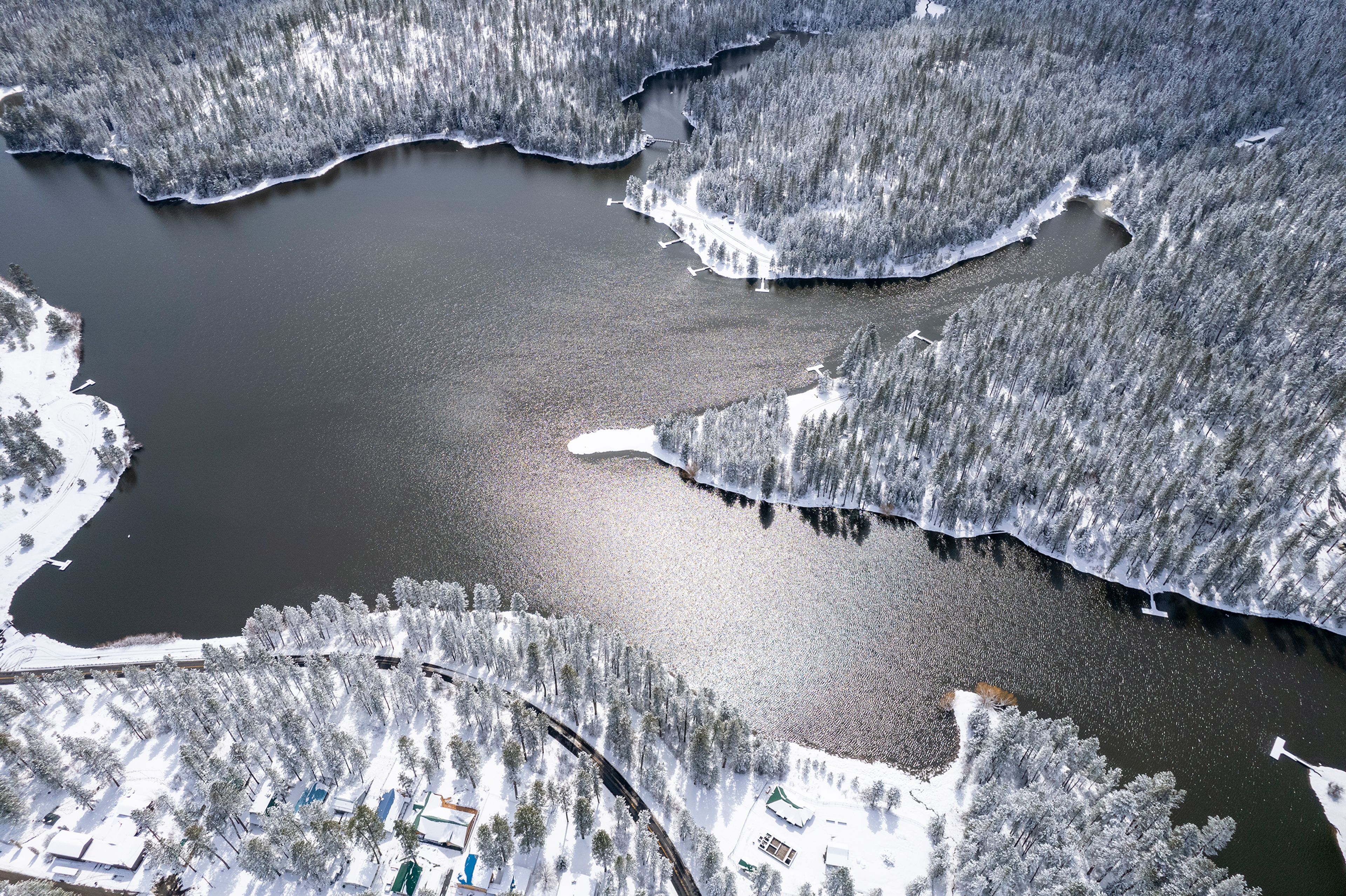 ABOVE: A photo captured with a drone shows Winchester Lake after a snowstorm April 12. The man-made lake was created in the 1960s following a fire that burned down a lumber mill. LEFT: Gregg Presnell, of Lewiston, enjoys a cool day of fishing at Winchester Lake with clouds drifting by overhead during the summer of 2021.