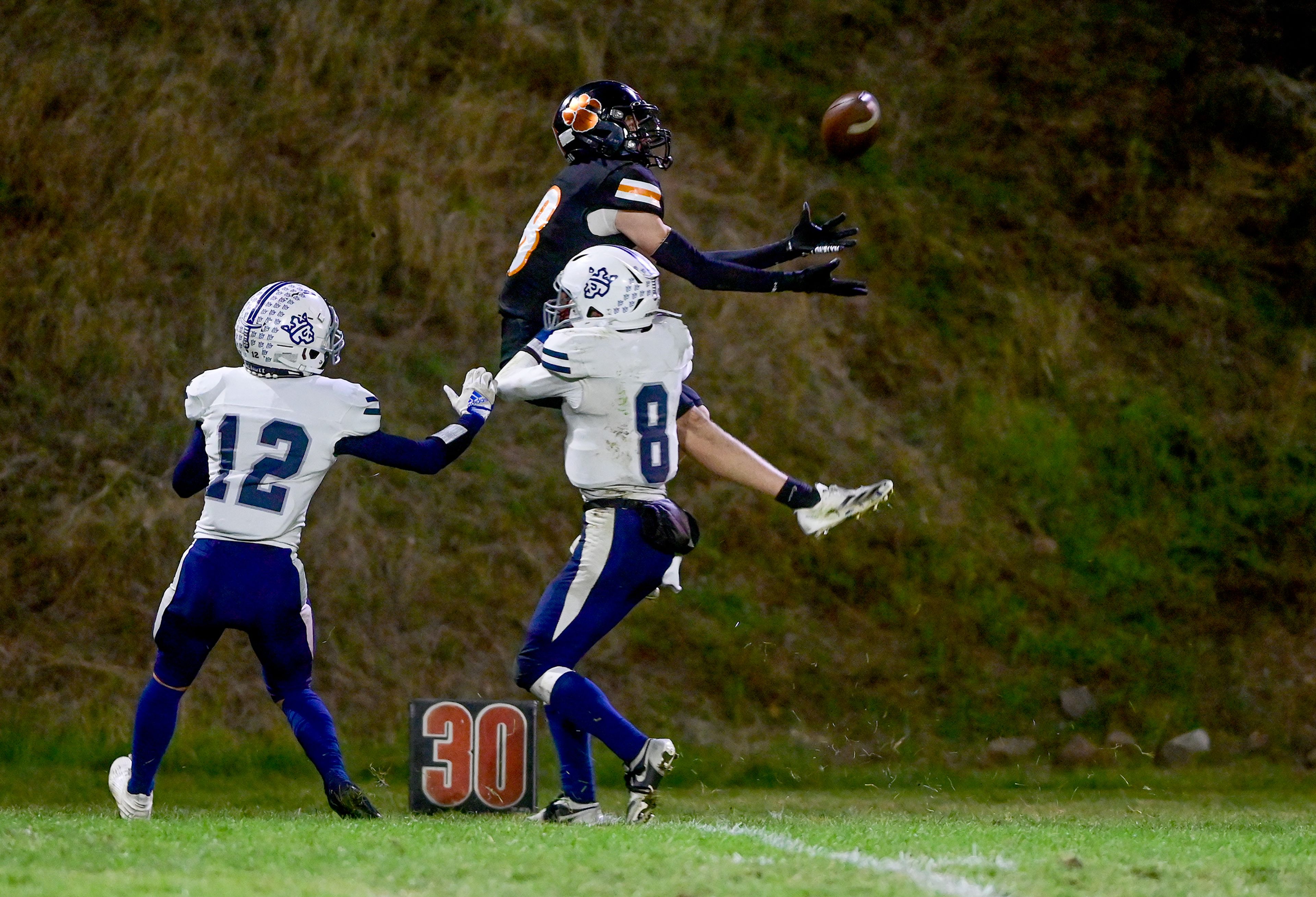 Kendrick�s Cade Silflow jumps to complete a pass with pressure from Logos� Ryan Daniels, left, and Seamus Willson Friday in Kendrick.,