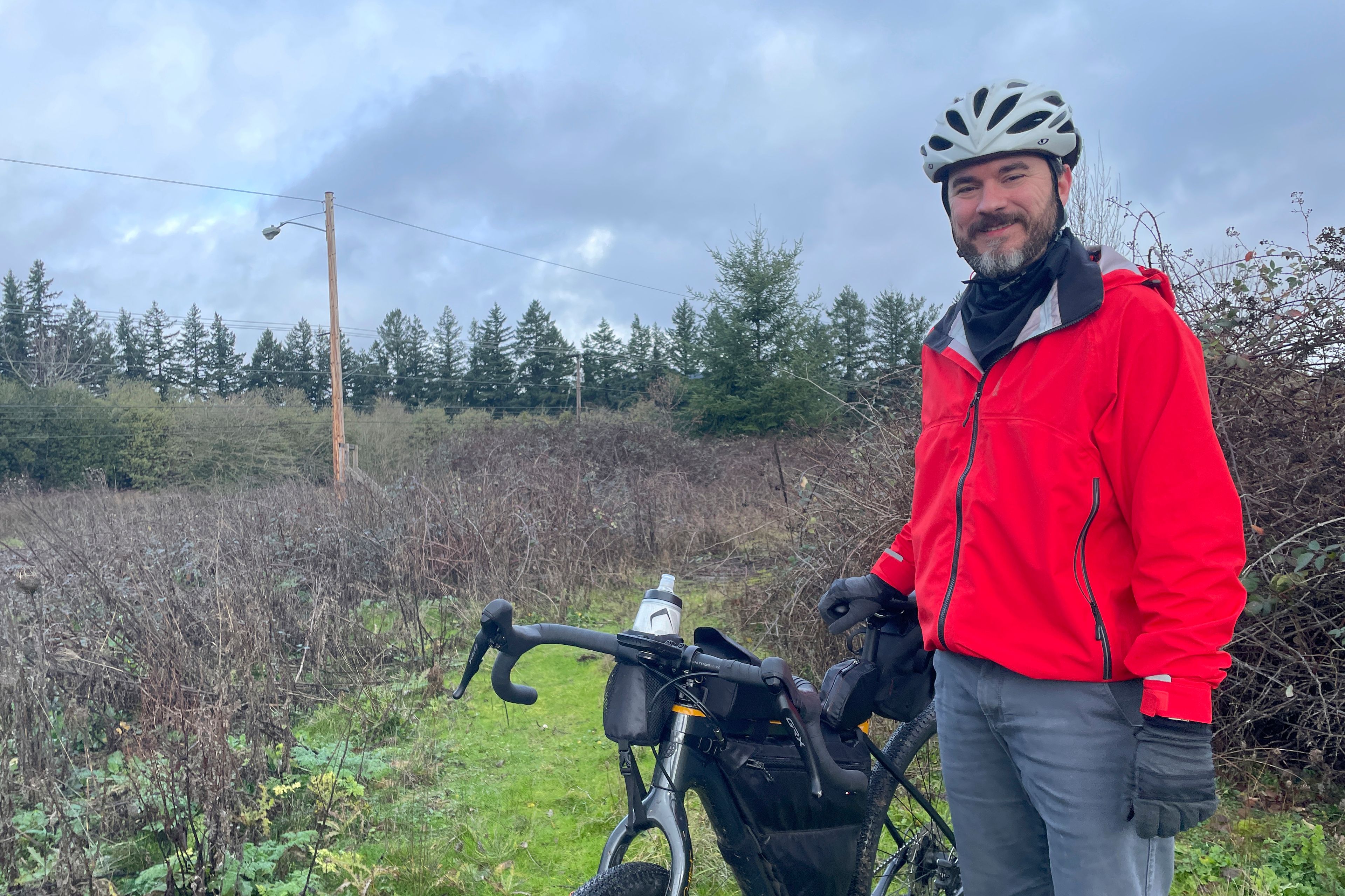 Adam Pirkle stands with his bicycle on the edge of a densely thicketed area in the Cedar Hills area of southwest Portland, Ore., Sunday, Jan. 7, 2024. Pirkle said he rode 14 miles looking for the wreckage of the exit door plug that detached from a Boeing 737 Max 9 shortly after the takeoff of an Alaska Airlines flight on Friday, Jan. 5. The National Transportation Safety Board estimated it may have fallen in the area. (AP Photo/Claire Rush)