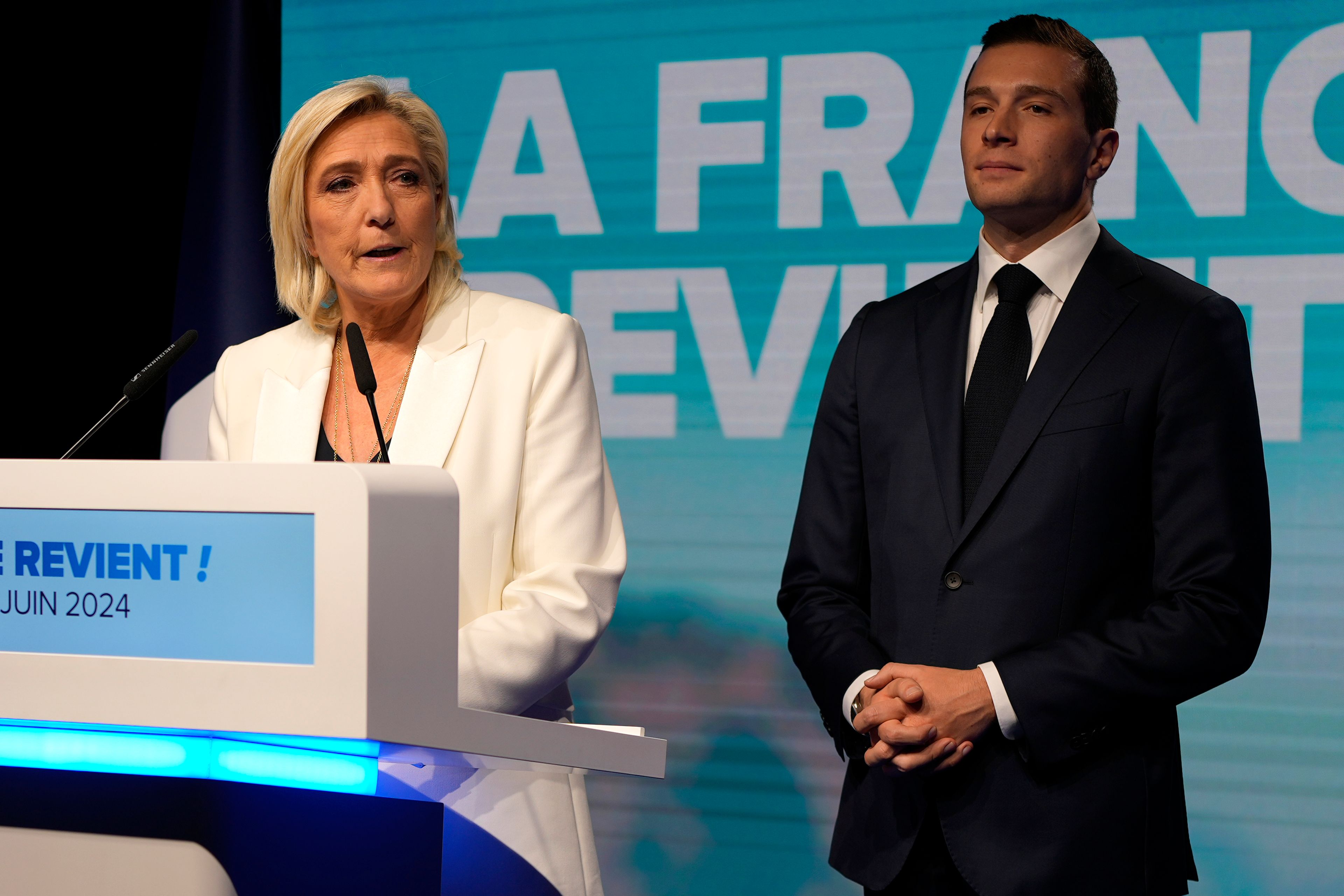 French far-right leader Marine Le Pen speaks as Jordan Bardella, president of the French far-right National Rally, listens at the party election night headquarters after French President Emanuel Macron announced he dissolves National Assembly and calls new legislative election after defeat in EU vote, Sunday, June 9, 2024 in Paris. First projected results from France put far-right National Rally party well ahead in EU elections, according to French opinion poll institutes.