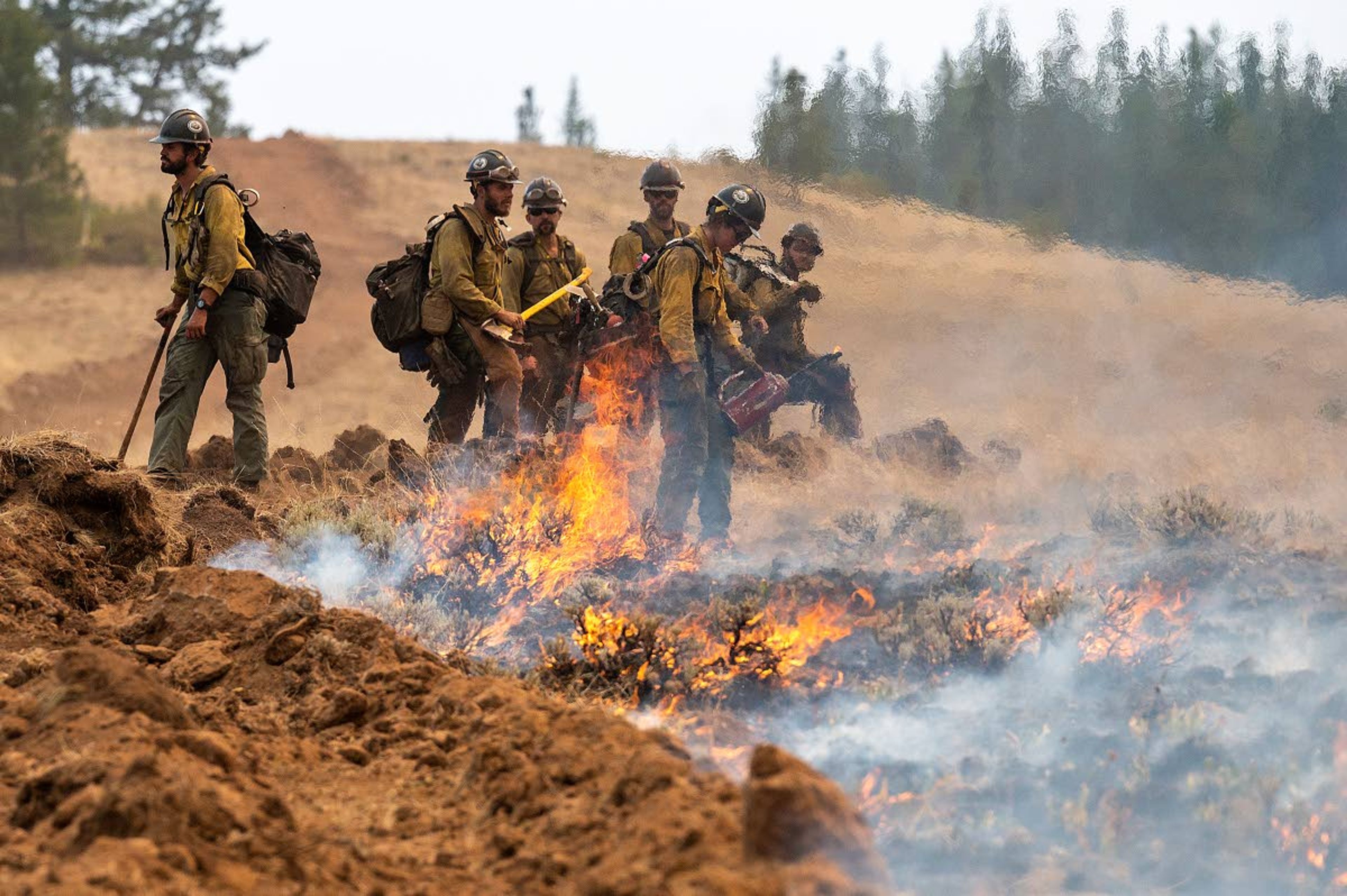 A wildland fire crew looks on after setting a fire line on Harlow Ridge above the Lick Creek Fire on Monday afternoon southwest of Asotin.