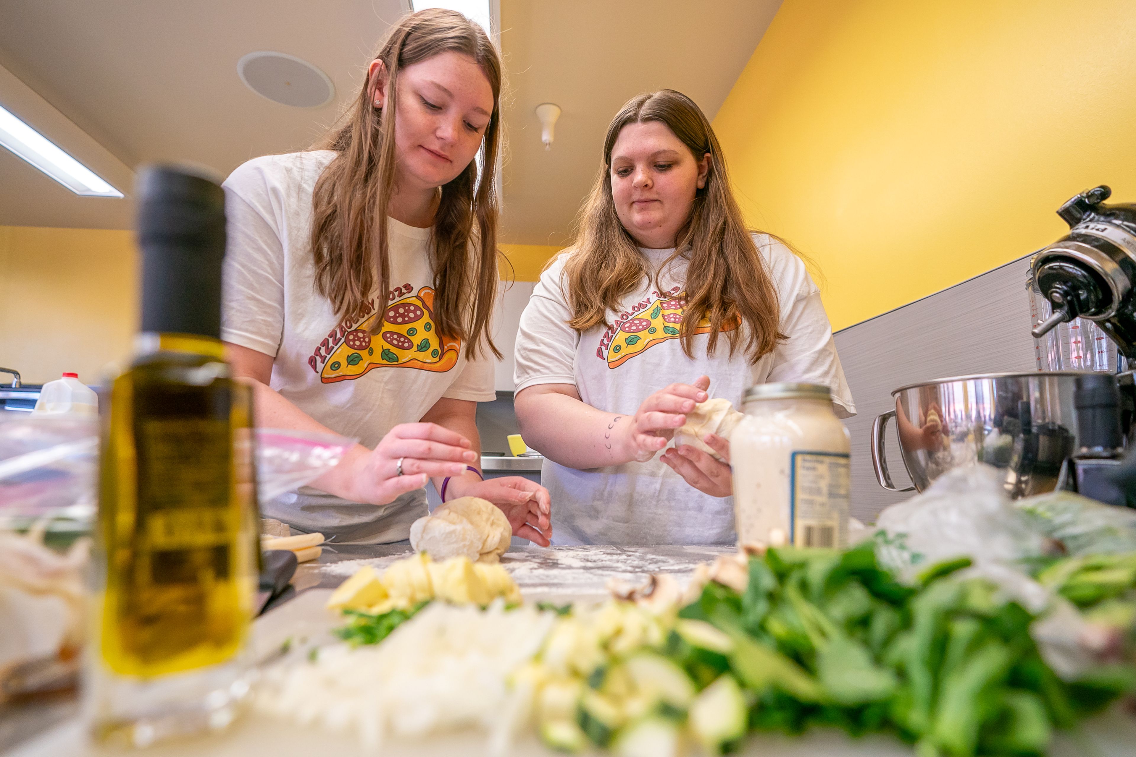 Hannah Wlash, left, 16, and Memory H., 17, both of Kellogg, begin kneading their dough during the final day of the 2023 Pizza-ology Camp on Wednesday at the Carmelita Spencer Food Laboratory in Moscow.