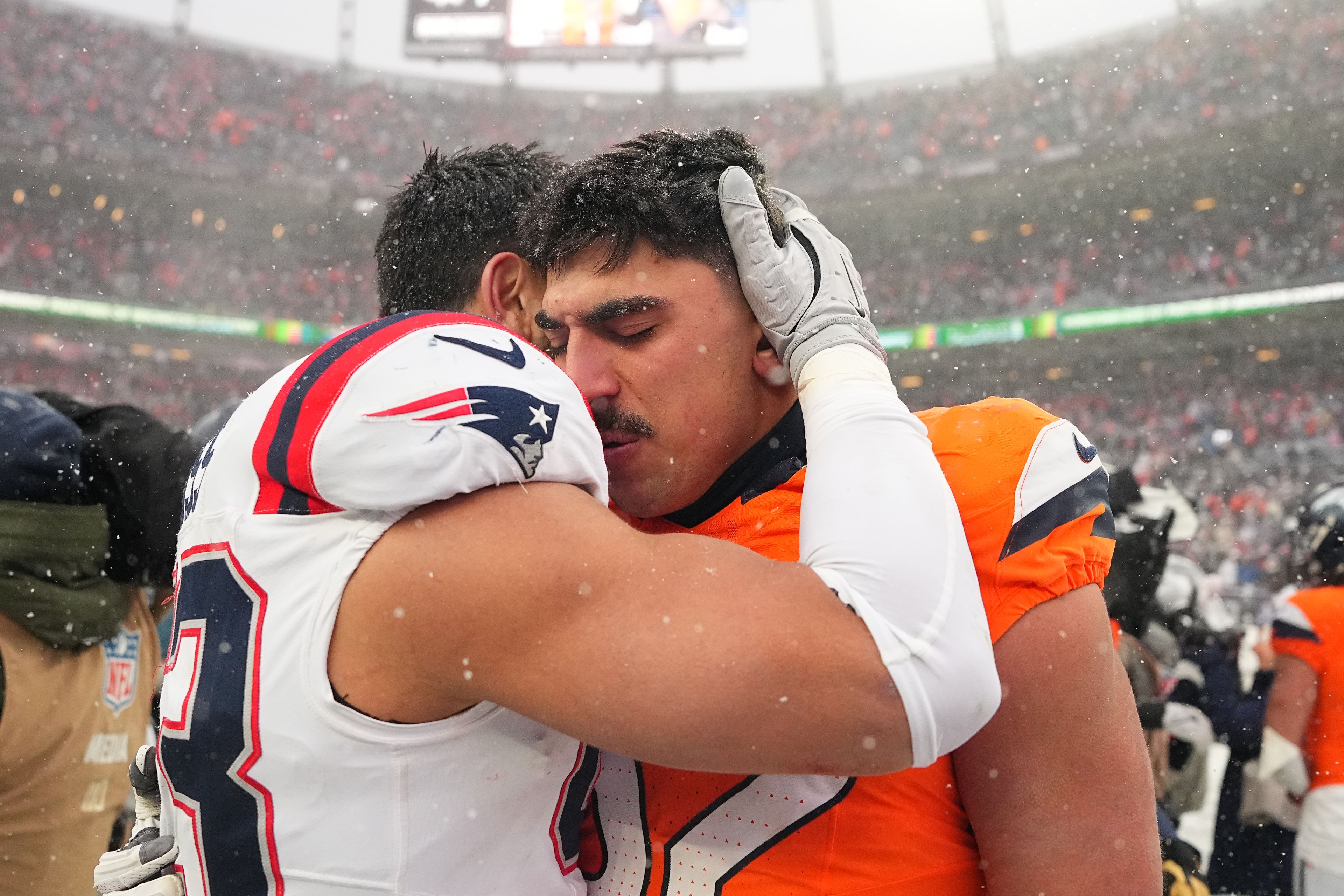 Patriots linebacker Christian Elliss (53) consoles his brother, Broncos linebacker Jonah Elliss (52), after the AFC Championship on Sunday in Denver.