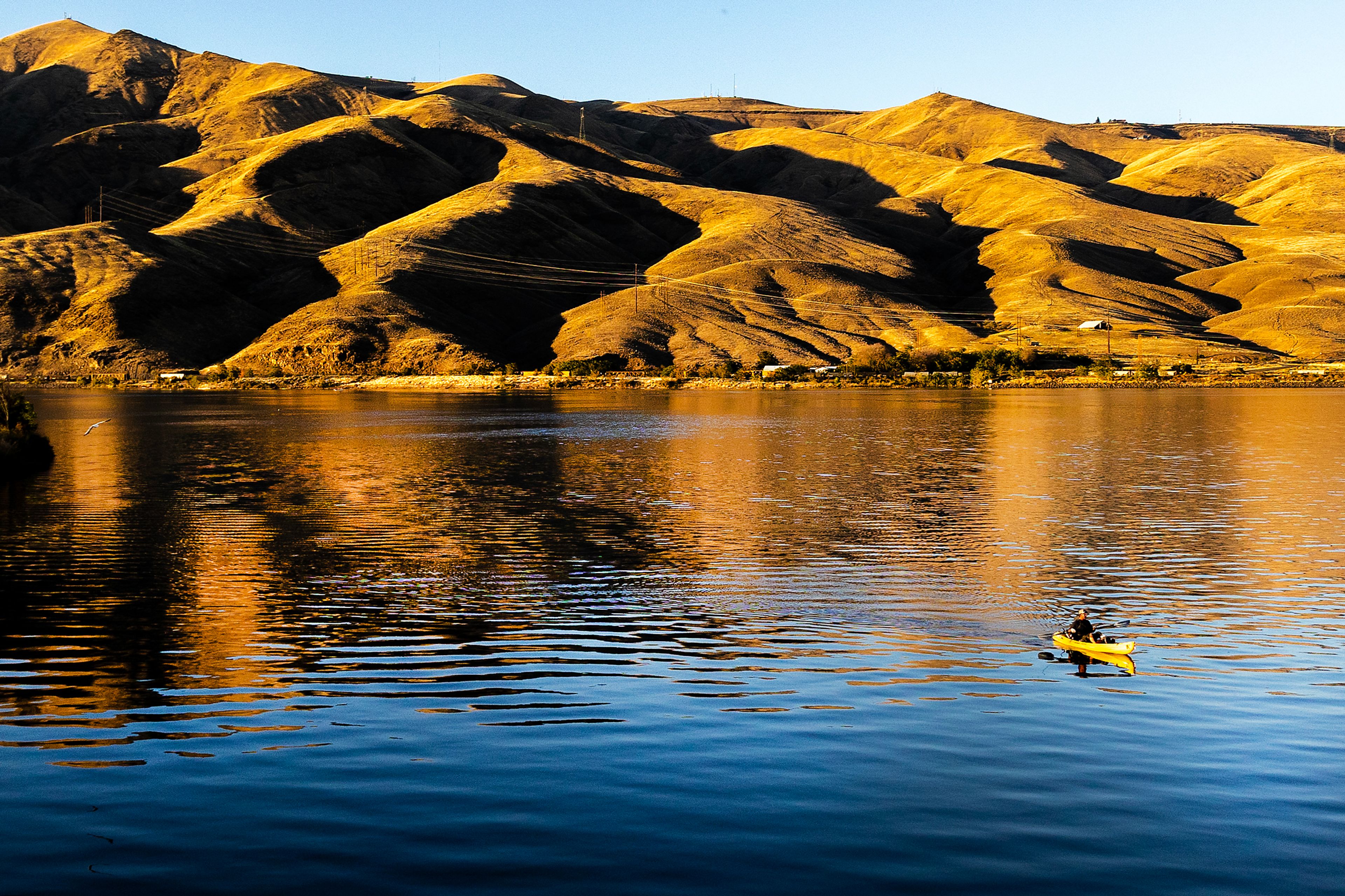 A person fishes on the confluence from a kayak as the setting sun turns the hills gold Monday near the Interstate Bridge.,