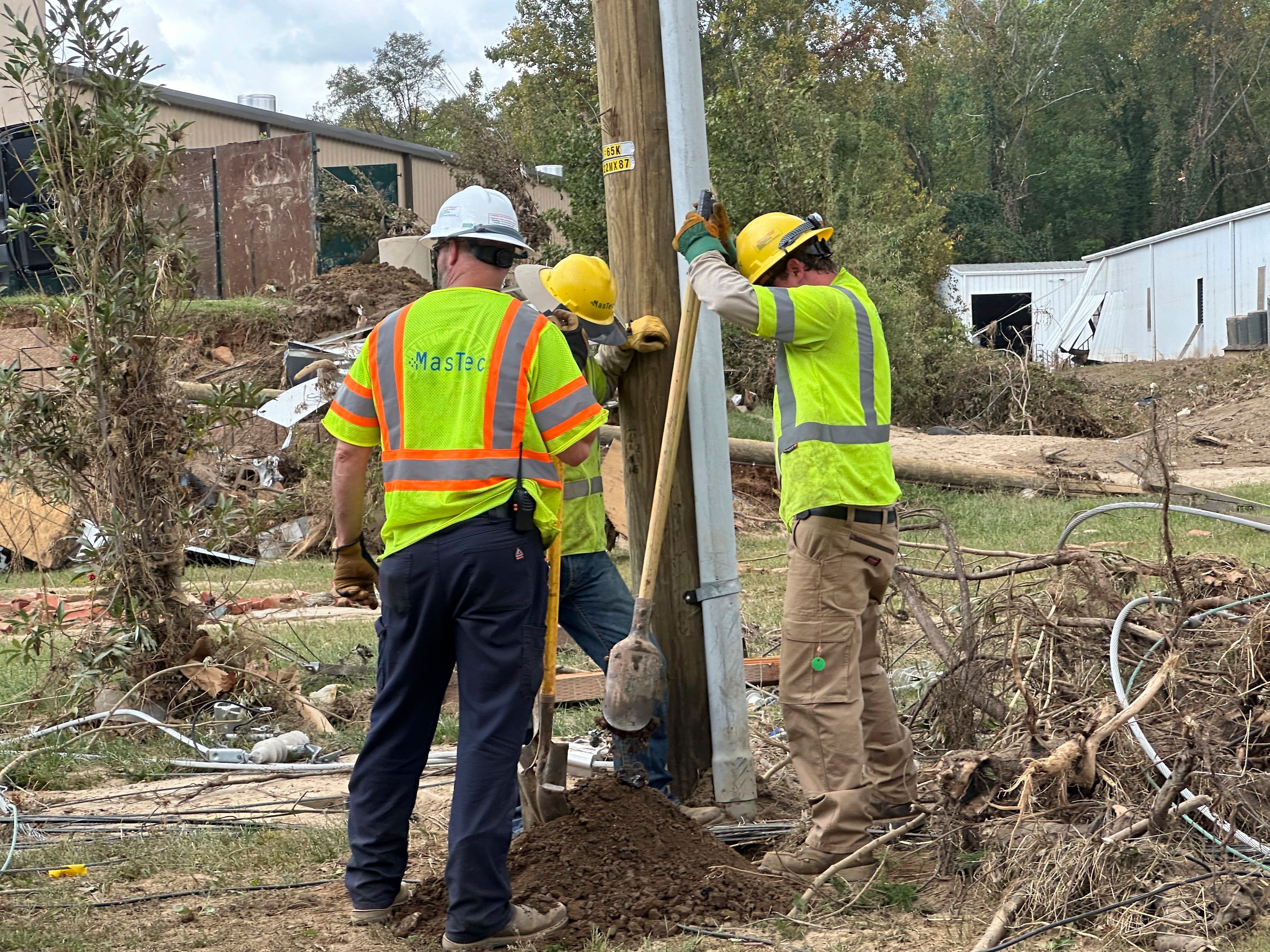 Contractors for Duke Energy dig a hole by hand to replace a utility pole in an area of destroyed electrical lines near the Swannanoa River in Asheville, N.C., on Friday, Oct. 4, 2024. (AP Photo/Jeff Amy)