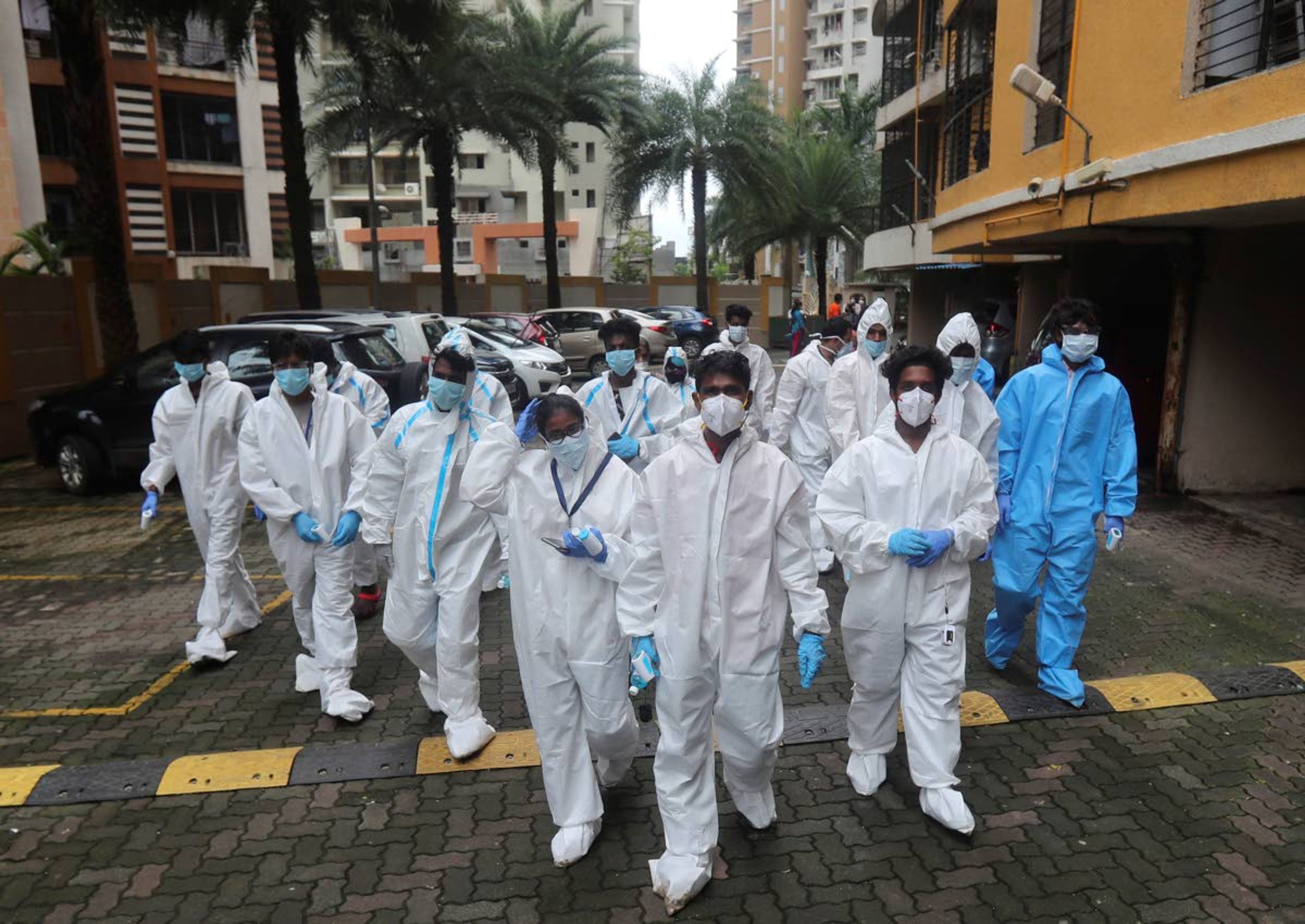 Health workers arrives to screen people for COVID-19 symptoms at a residential building in Mumbai, India, Sunday, July 26, 2020. India is the third hardest-hit country by the pandemic in the world after the United States and Brazil. (AP Photo/Rafiq Maqbool)