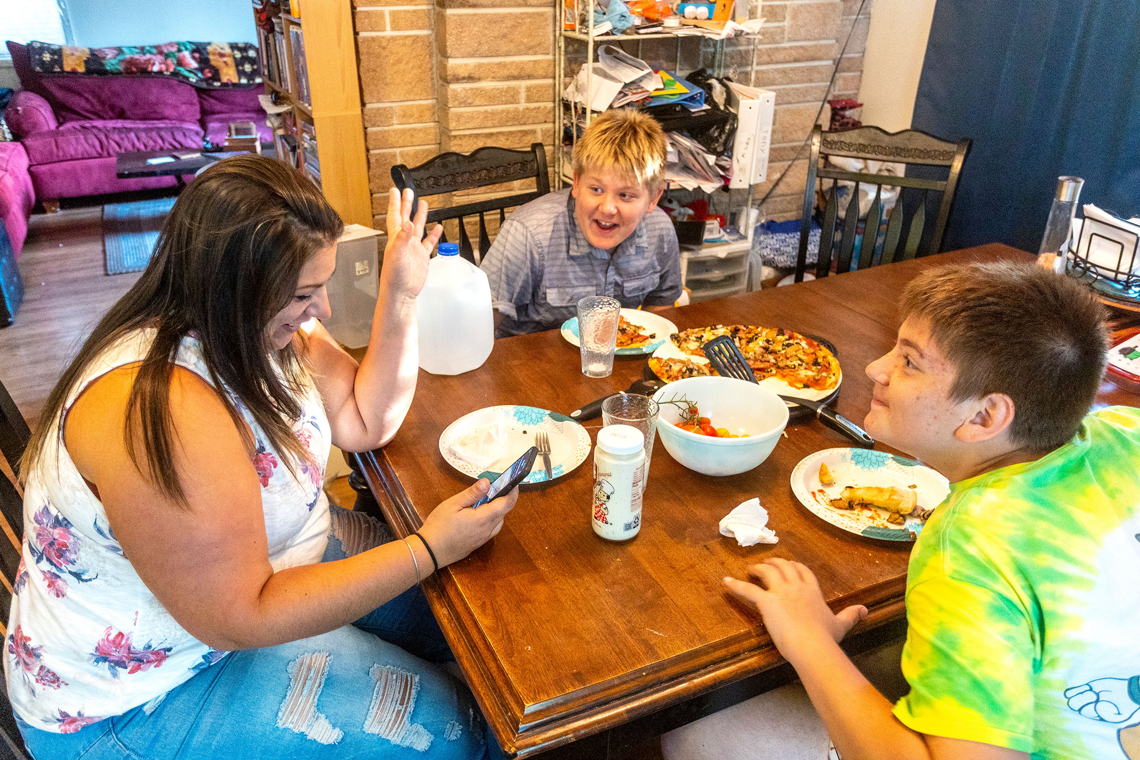 Alex Poulsen, right, and Tony Poulsen react as their mother, Aimee Martinez, looks up the name of one of their teachers that they say was in a boy band, while at their home Friday in Moscow.