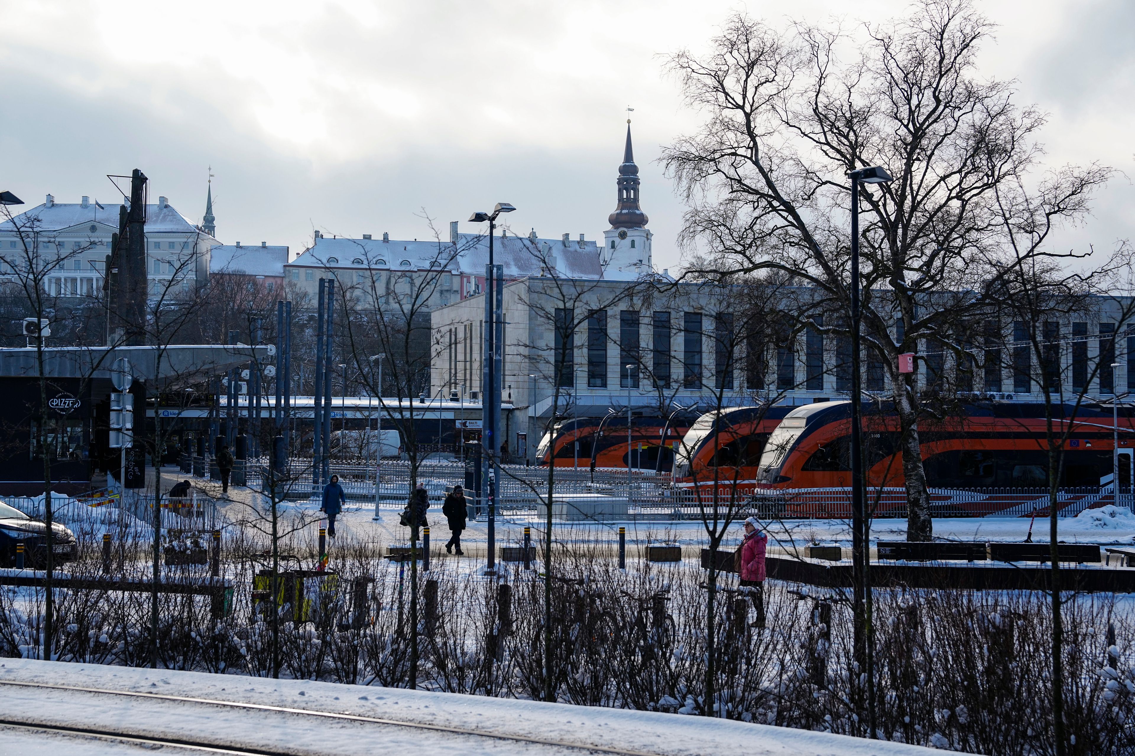 FILE - People walk at Baltic train station, with the Stenbock House, left, and St Mary's Cathedral, top, in background, in Tallinn, Estonia, Wednesday, Feb. 22, 2023.