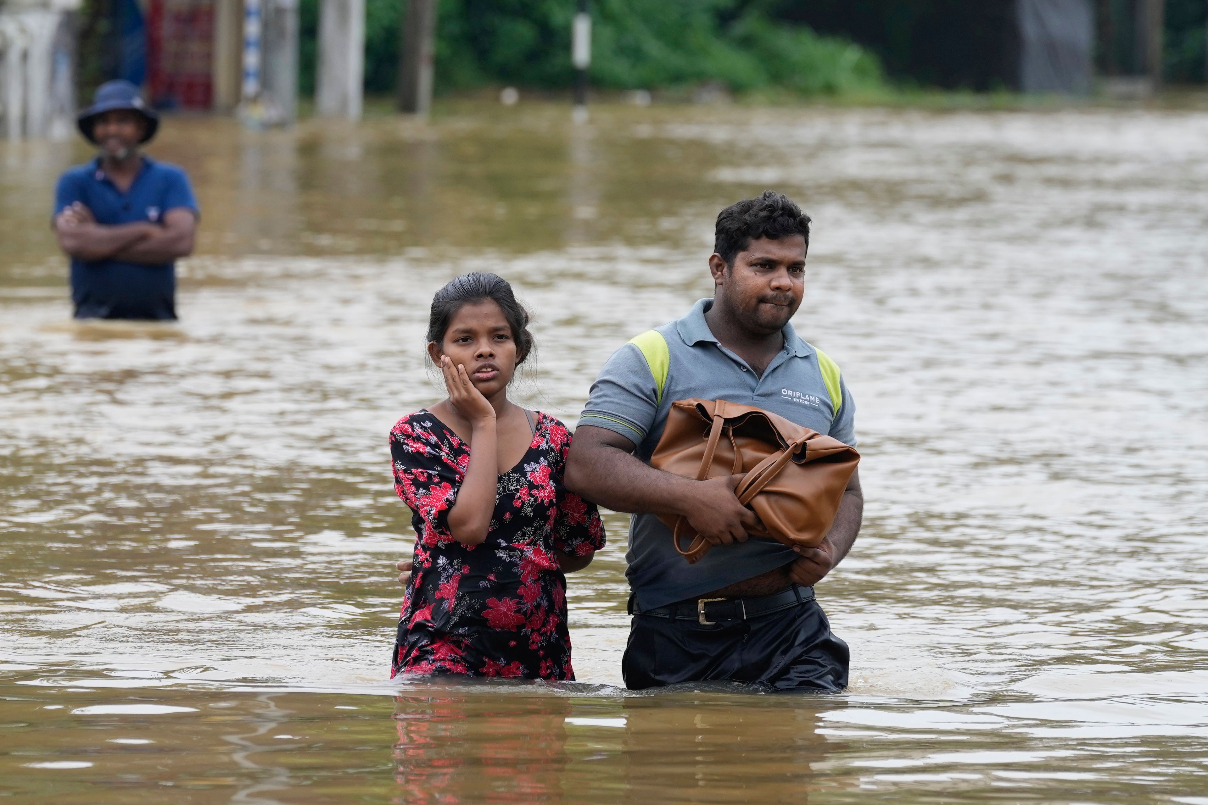 People wade through flood waters in Kelaniya, a suburb of Colombo, Sri Lanka, Monday, June 3, 2024. Sri Lanka closed schools on Monday as heavy rains triggered floods and mudslides in many parts of the island nation, killing at least 10 people while six others have gone missing, officials said.