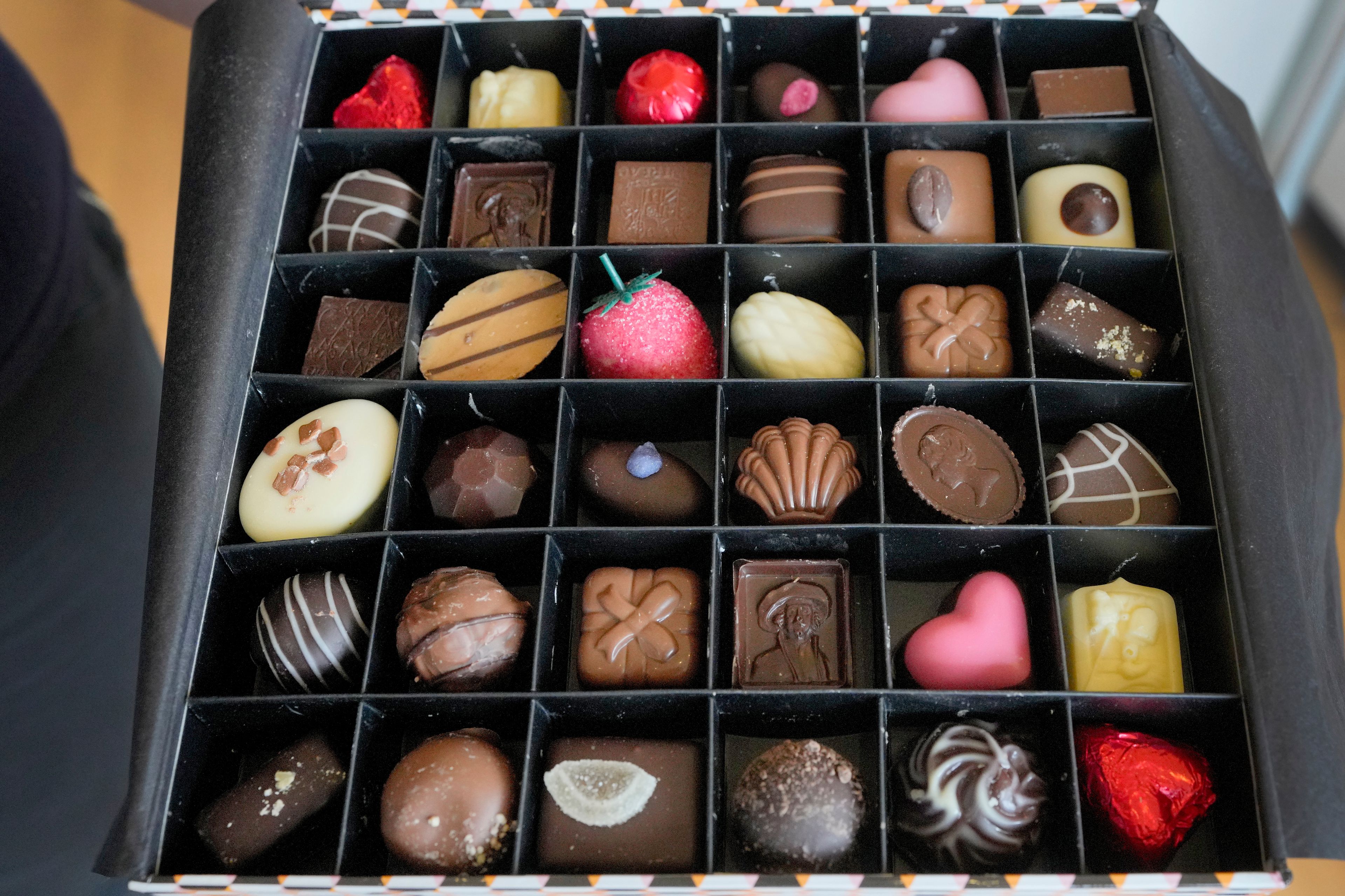 A selection box of luxury handmade Belgian Chocolates is displayed at Sandrine a chocolate shop owned by Niaz Mardan, in south west London, Thursday, March 21, 2024. Niaz Mardan, is suffering due to high cocoa prices, she's making no profits and fears she will have to close the shop that's been around for 25 years (she's the third owner and took over in 2019). (AP Photo/Kirsty Wigglesworth)