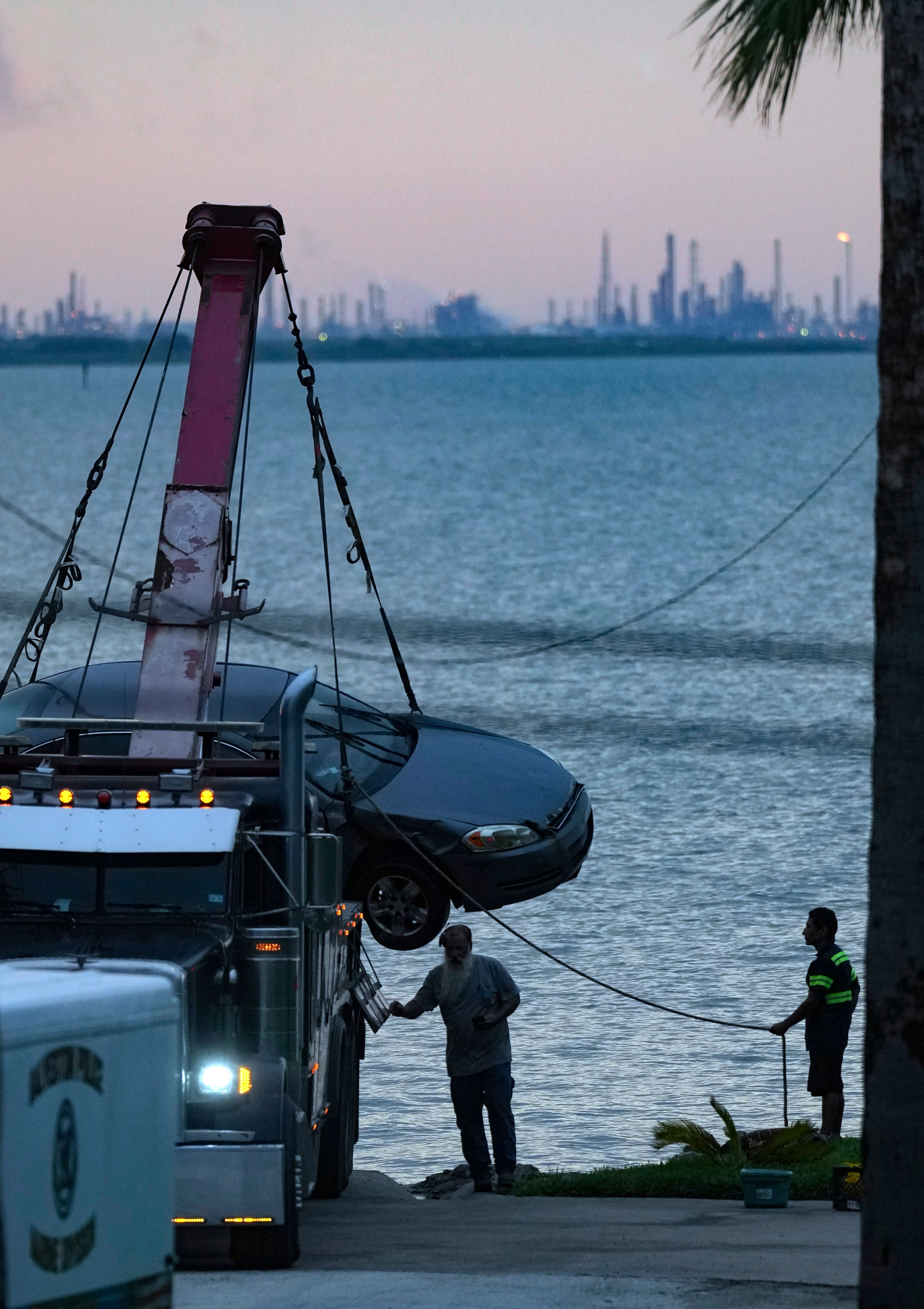 Tow truck operators pull a car out of the Galveston Ship Channel Tuesday, Sept. 3, 2024 in Galveston, Texas, following the fatal shooting of a Texas deputy constable in Houston. A suspect led authorities on a 60 miles chase that ended in the waters off Galveston, where the man tried swimming away to evade arrest before being captured with the help of a marine unit, according to the Port of Galveston Police Department.