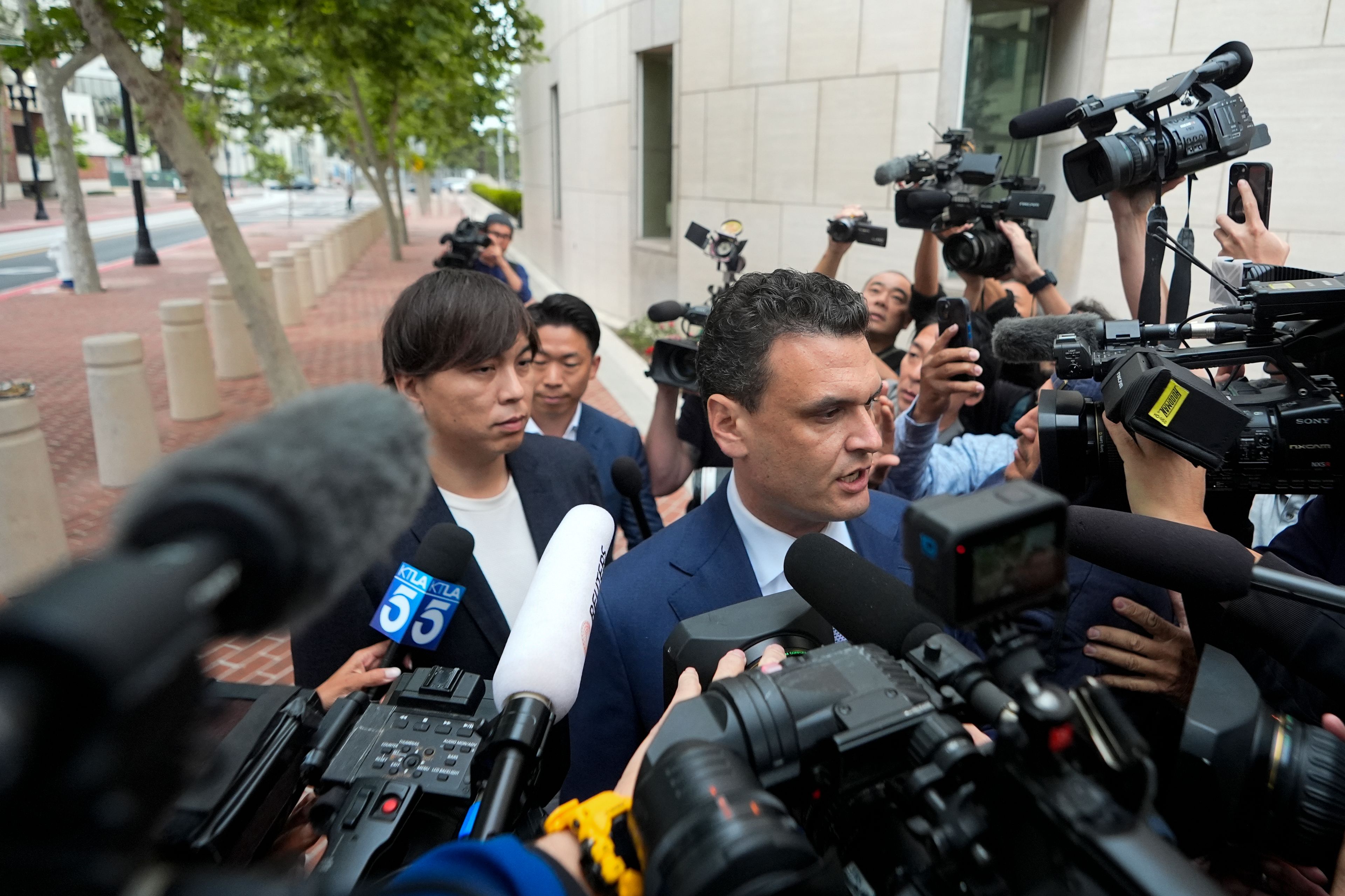 Ippei Mizuhara, the former longtime interpreter for the Los Angeles Dodgers baseball star Shohei Ohtani, stands behind his defense attorney Michael Freedman, as he talks to the media outside federal court in Los Angeles, Tuesday, June 4, 2024. Mizuhara is scheduled to plead guilty Tuesday to bank and tax fraud in a sports betting case where he is expected to admit to stealing nearly $17 million from the Japanese baseball player.