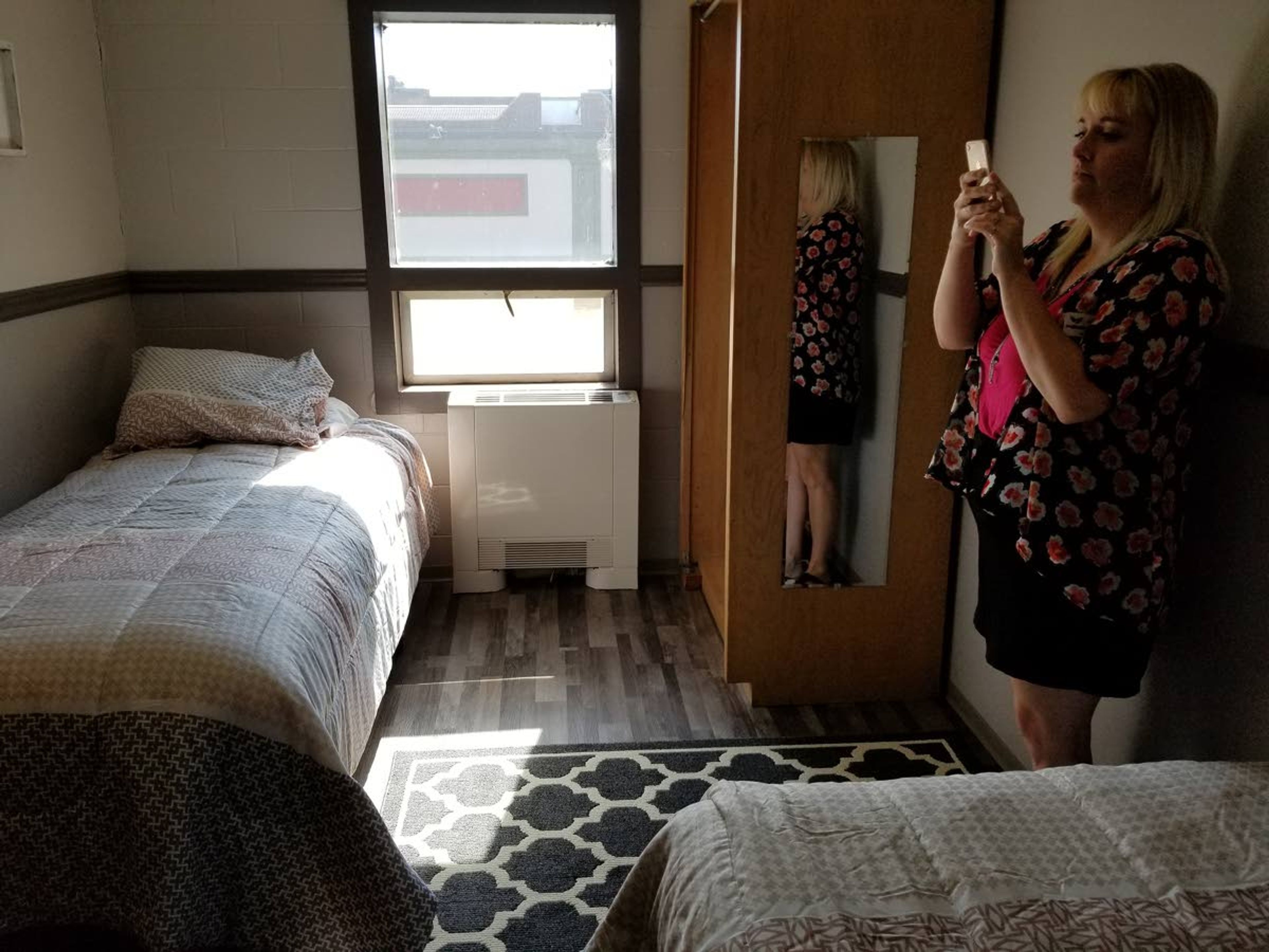 Amanda Wilhelm, YWCA director of community engagement, takes a photo of a newly refurbished room.