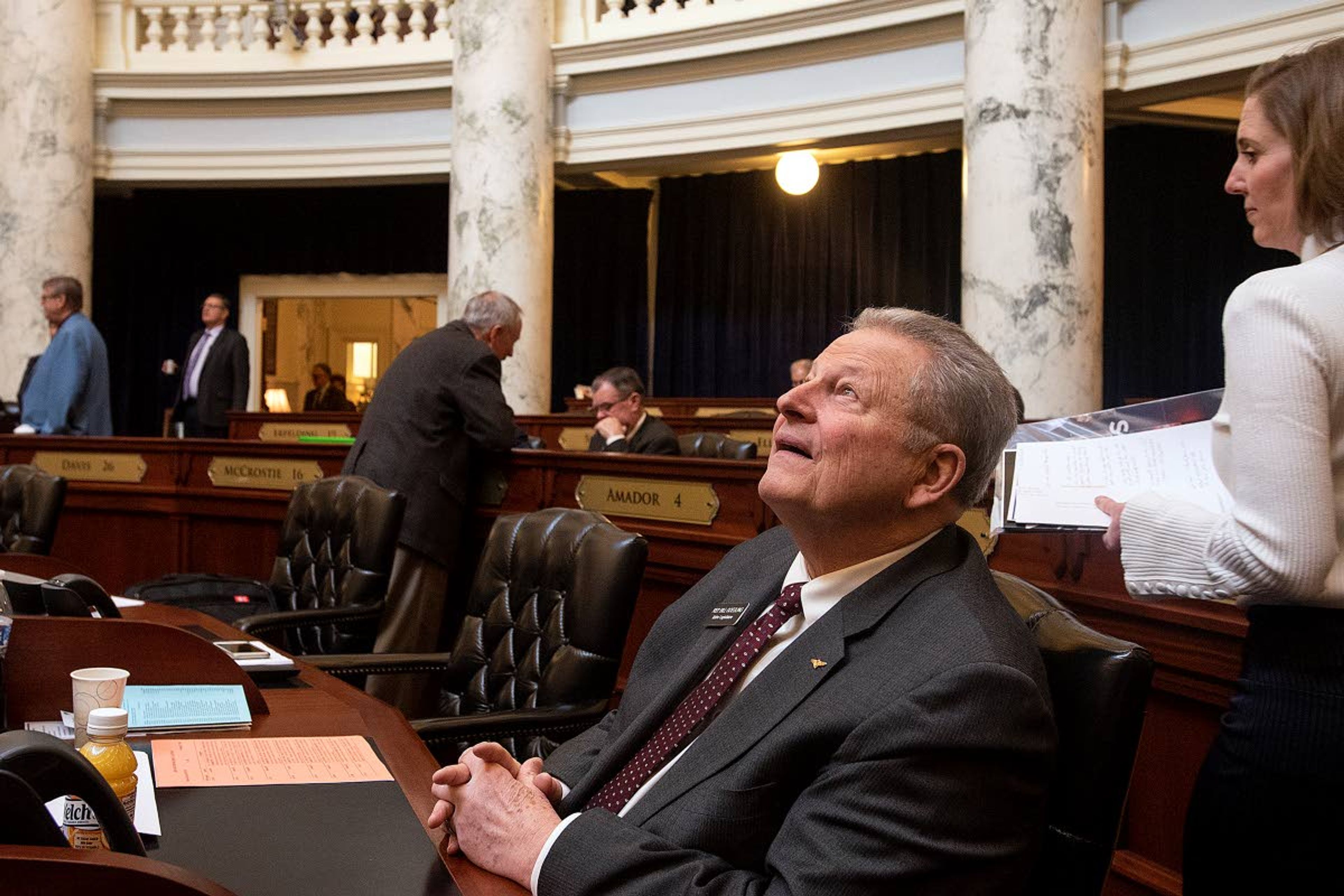 Rep. Bill Goesling, R-Moscow, looks up at the skylight as the sun breaks through the clouds over the Treasure Valley before the session gets underway on a recent day in the Idaho House of Representatives in Boise. Goesling, a retired U.S. Navy aviator, said his first job was helping neighbors move heavy cast-iron trash cans from the curb when he was a young child.