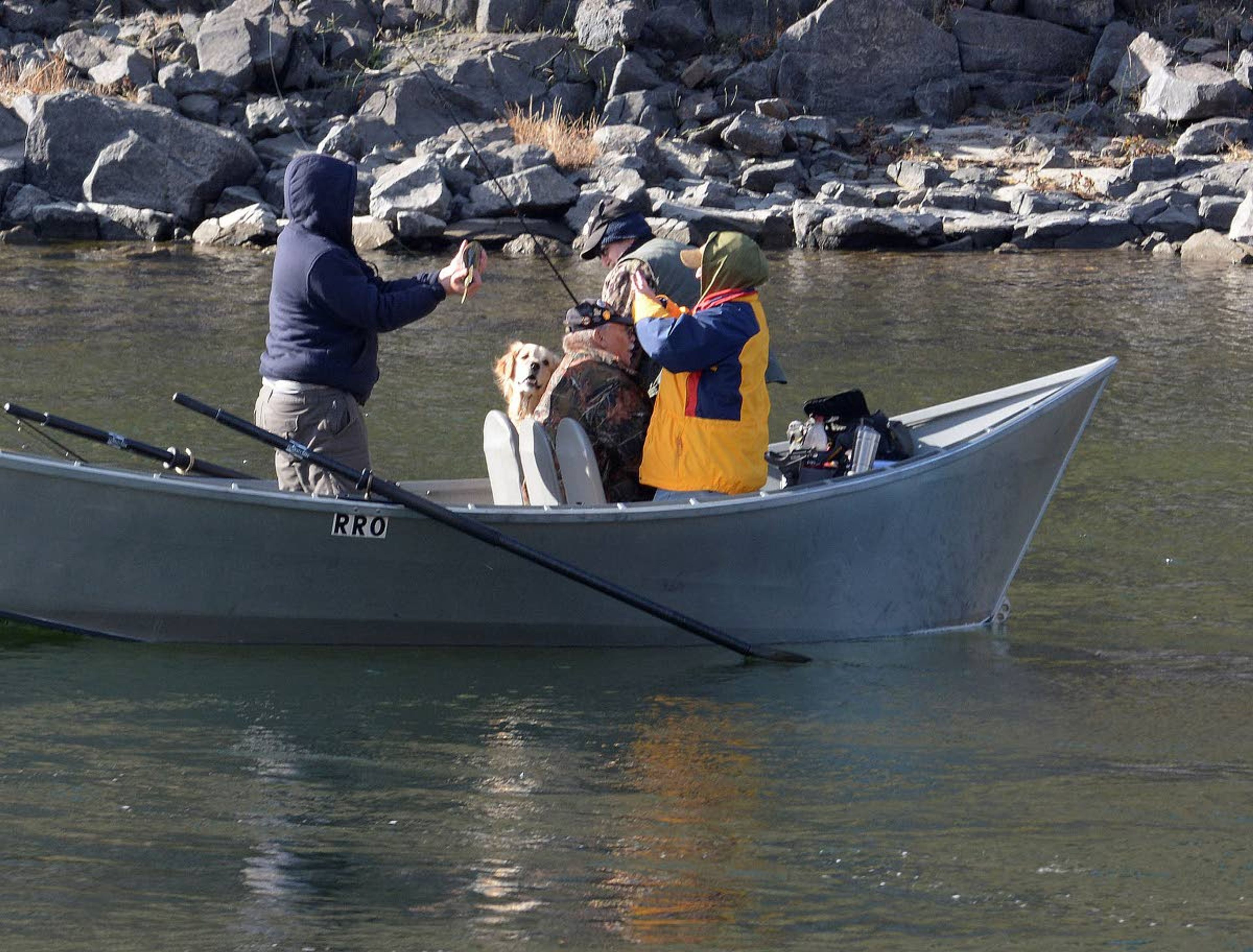 A Rapid River Outfitters guide holds a steelhead up for a client to capture a memory of it.