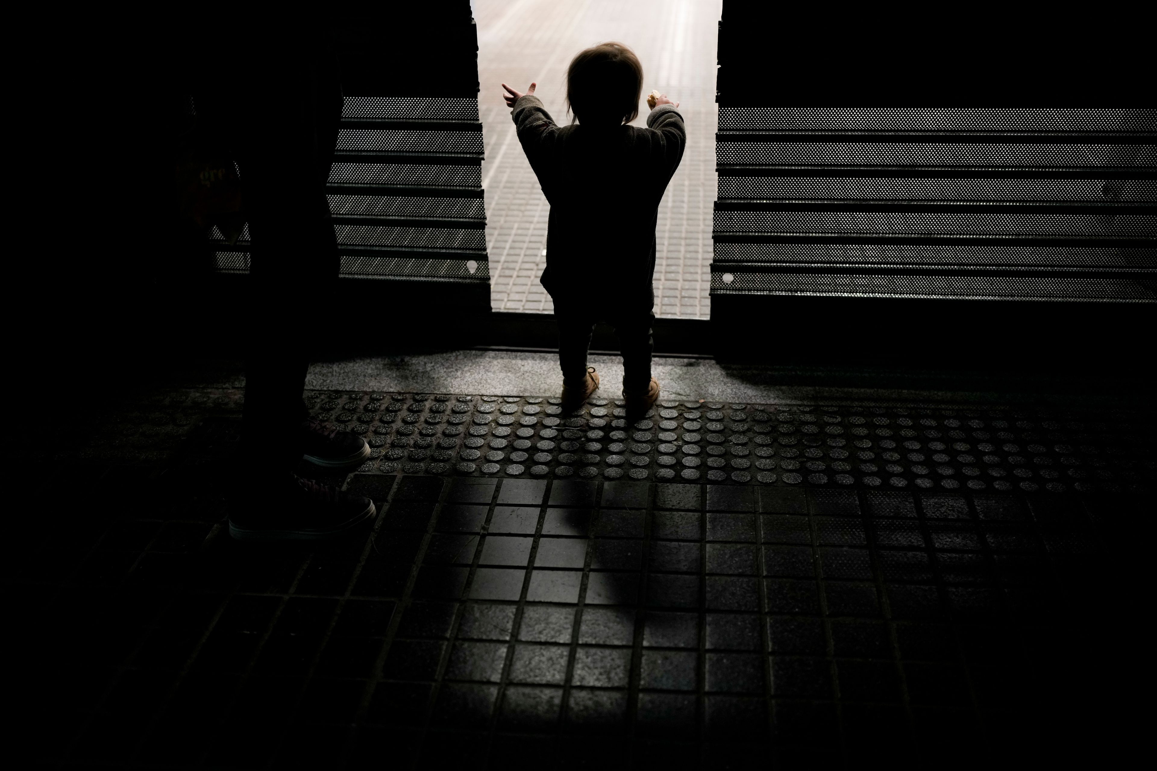 Felipe reaches through the door of a bakery where his parents Walter and Evelyn wait to take home discarded baked goods that the shop didn't sell in Buenos Aires, Argentina, Tuesday, Sept. 3, 2024. (AP Photo/Natacha Pisarenko)