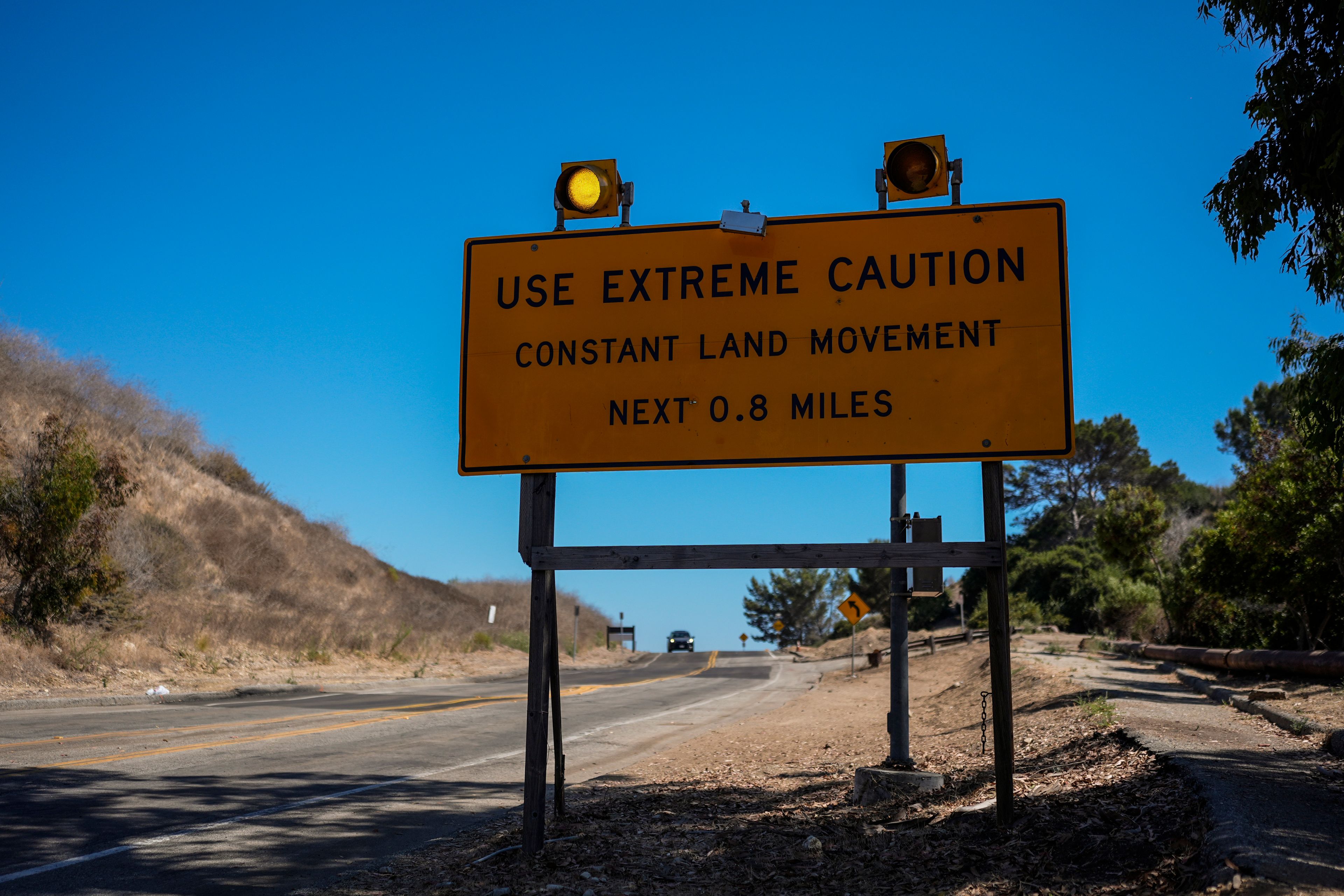 A warning sign stands along a section of road affected by ongoing landslides in Rancho Palos Verdes, Calif., Tuesday, Sept. 3, 2024.