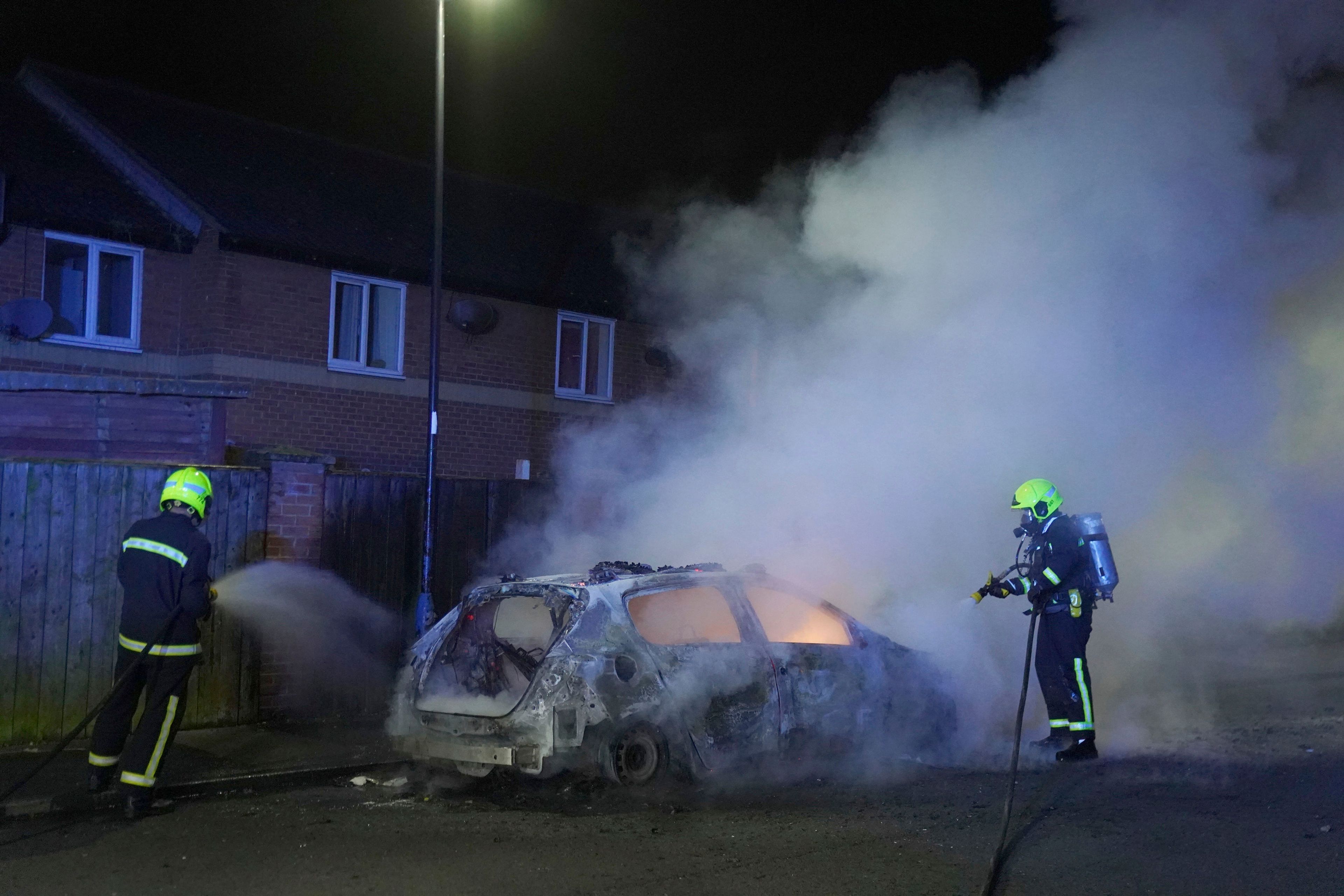 Firefighters tend to a burning police car as police officers are deployed on the streets of Hartlepool, England, following a violent protest in the wake of the killing of three girls who were fatally stabbed in northwest England, Wednesday, July 31, 2024. (Owen Humphreys/PA via AP)