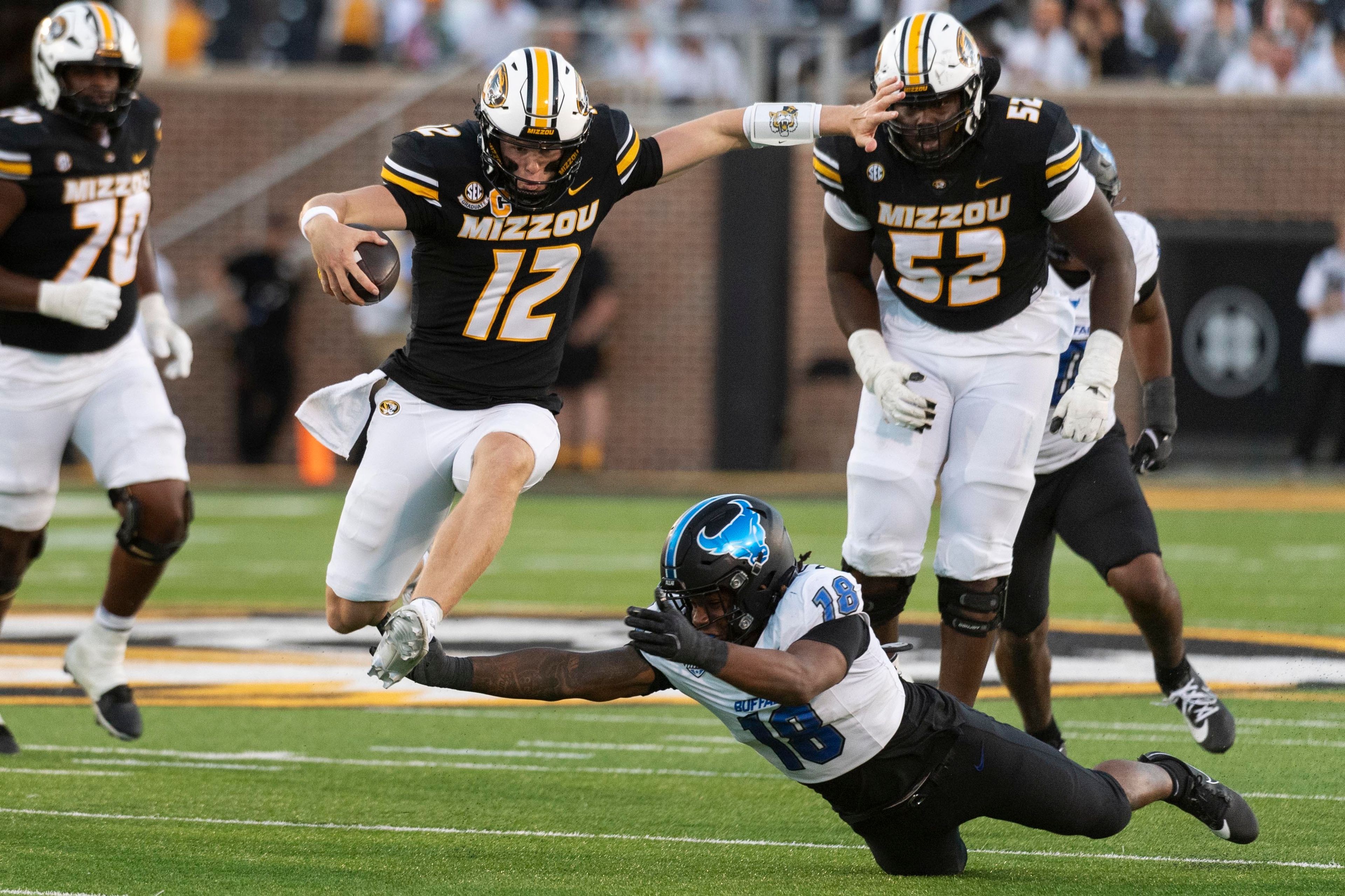 Missouri quarterback Brady Cook (12) leaps over Buffalo linebacker Dion Crawford (18) as he runs for touchdown during the first half of an NCAA college football game Saturday, Sept. 7, 2024, in Columbia, Mo. (AP Photo/L.G. Patterson)