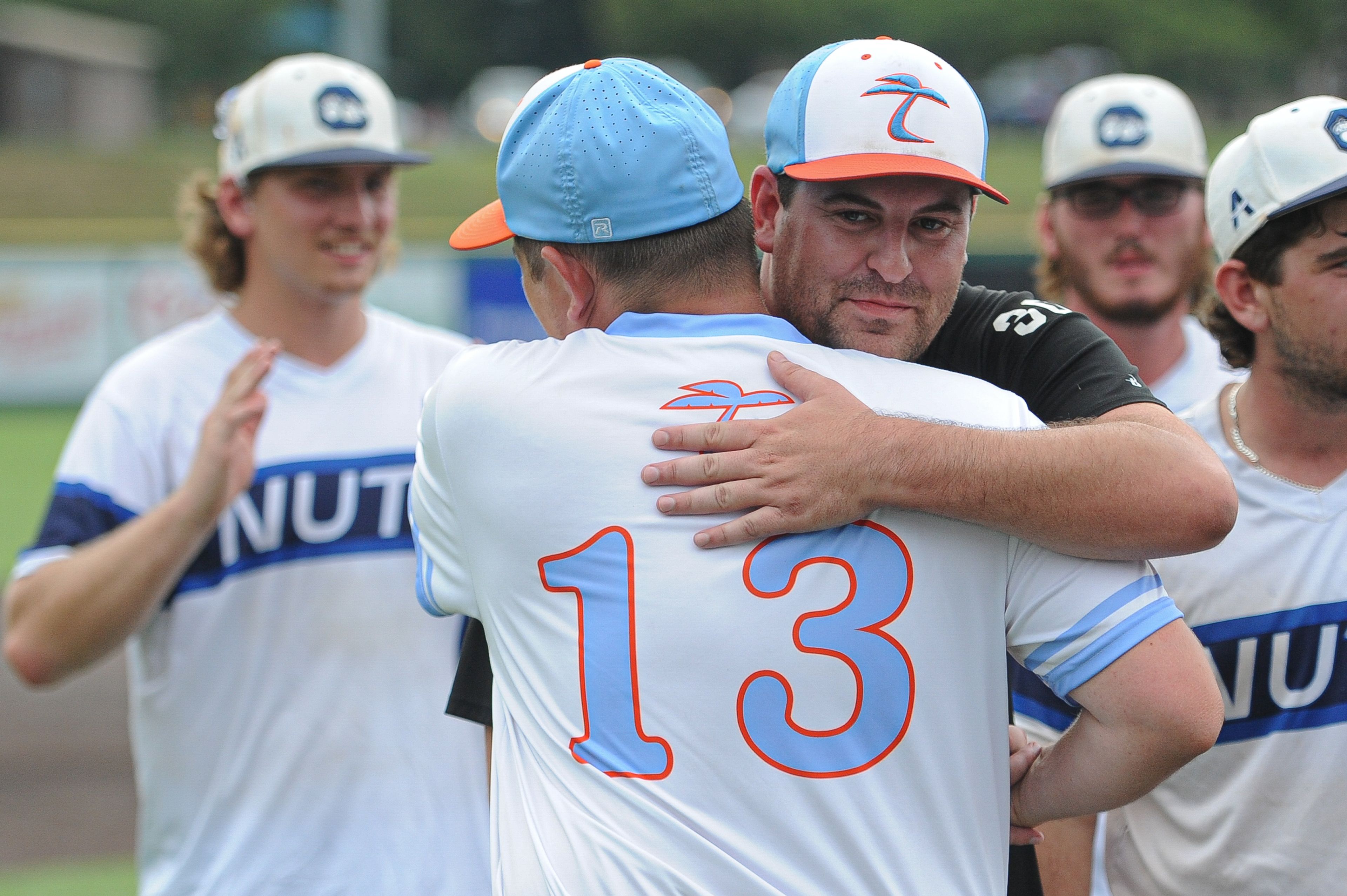 Southeast coaches Dustin Schwartz (center) and Mac McConnell (right) embrace following the August 15, 2024 Babe Ruth World Series third-place game between the Charleston Fighting Squirrels and the Southeast Tropics at Capaha Field in Cape Girardeau, Mo. Southeast defeated Charleston, 11-2 in five innings.