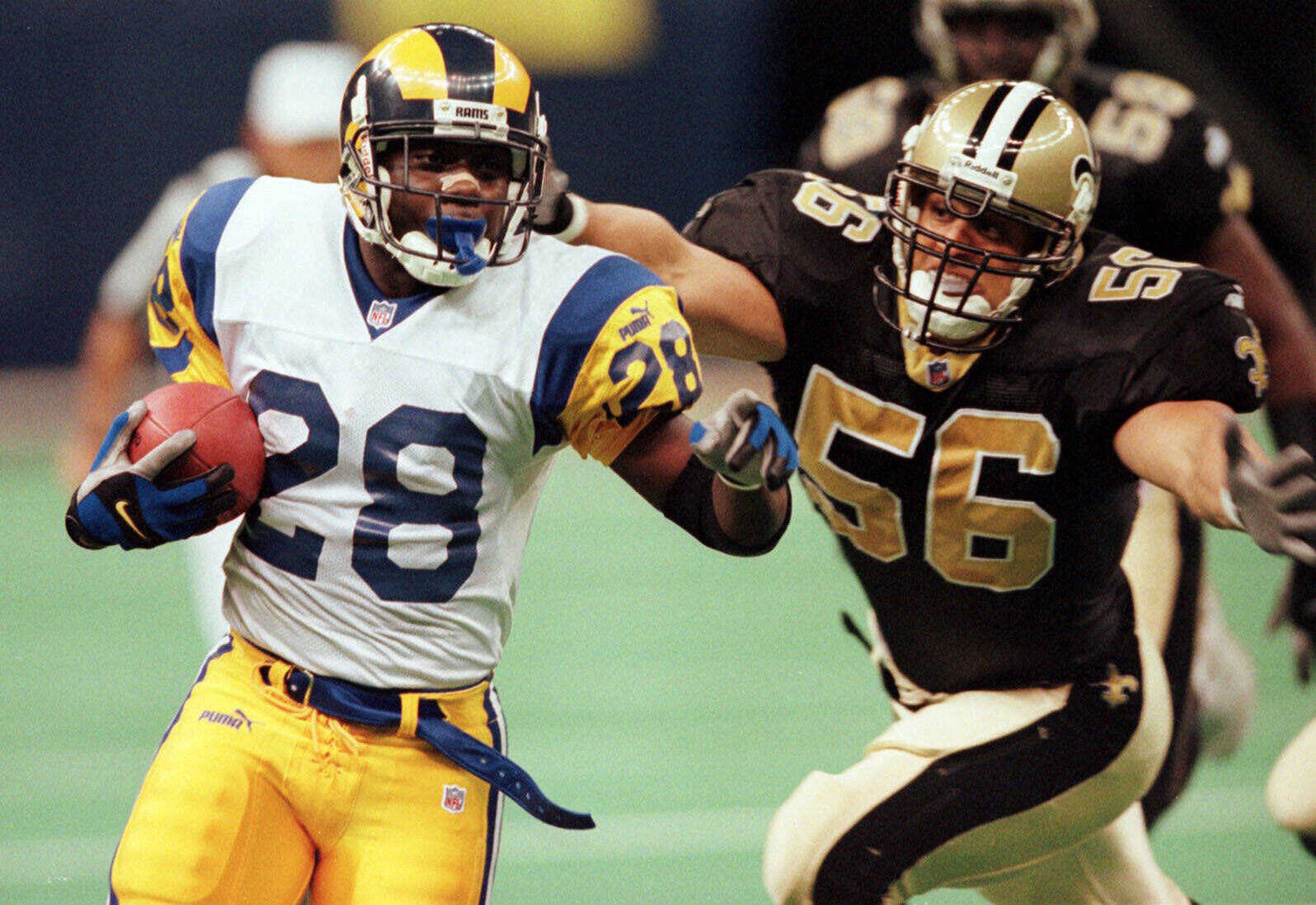 St. Louis Rams running back Marshall Faulk (28) carries the ball downfield as he is pursued by New Orleans Saints linebacker Chris Bordano (56) at the Louisiana Superdome on Sunday, Dec. 12, 1999.