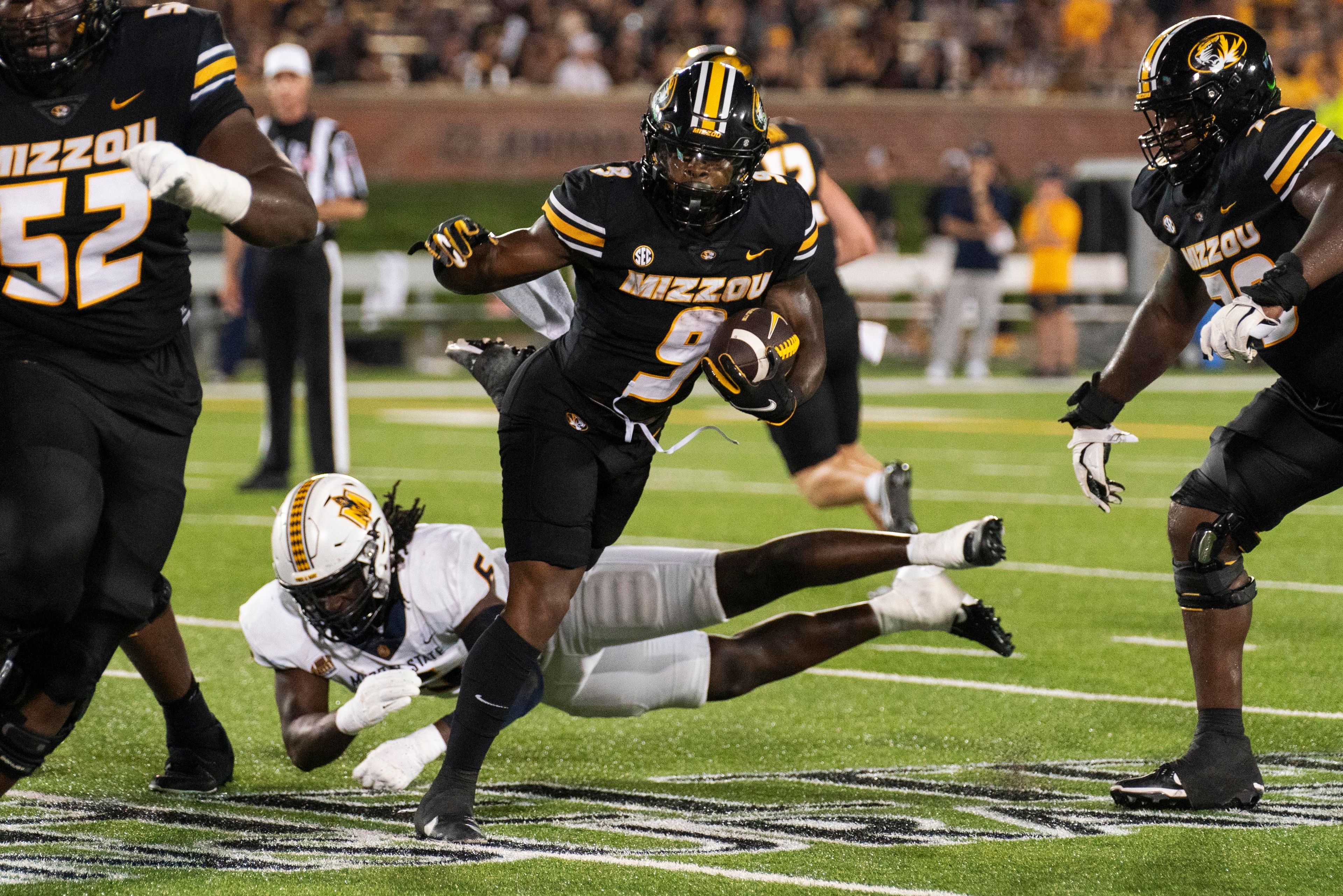 Missouri running back Marcus Carroll (9) gets tripped up by Murray State defensive lineman Kevon Haigler during the second half of an NCAA college football game Thursday, Aug. 29, 2024, in Columbia, Mo. Missouri won 51-0. (AP Photo/L.G. Patterson)