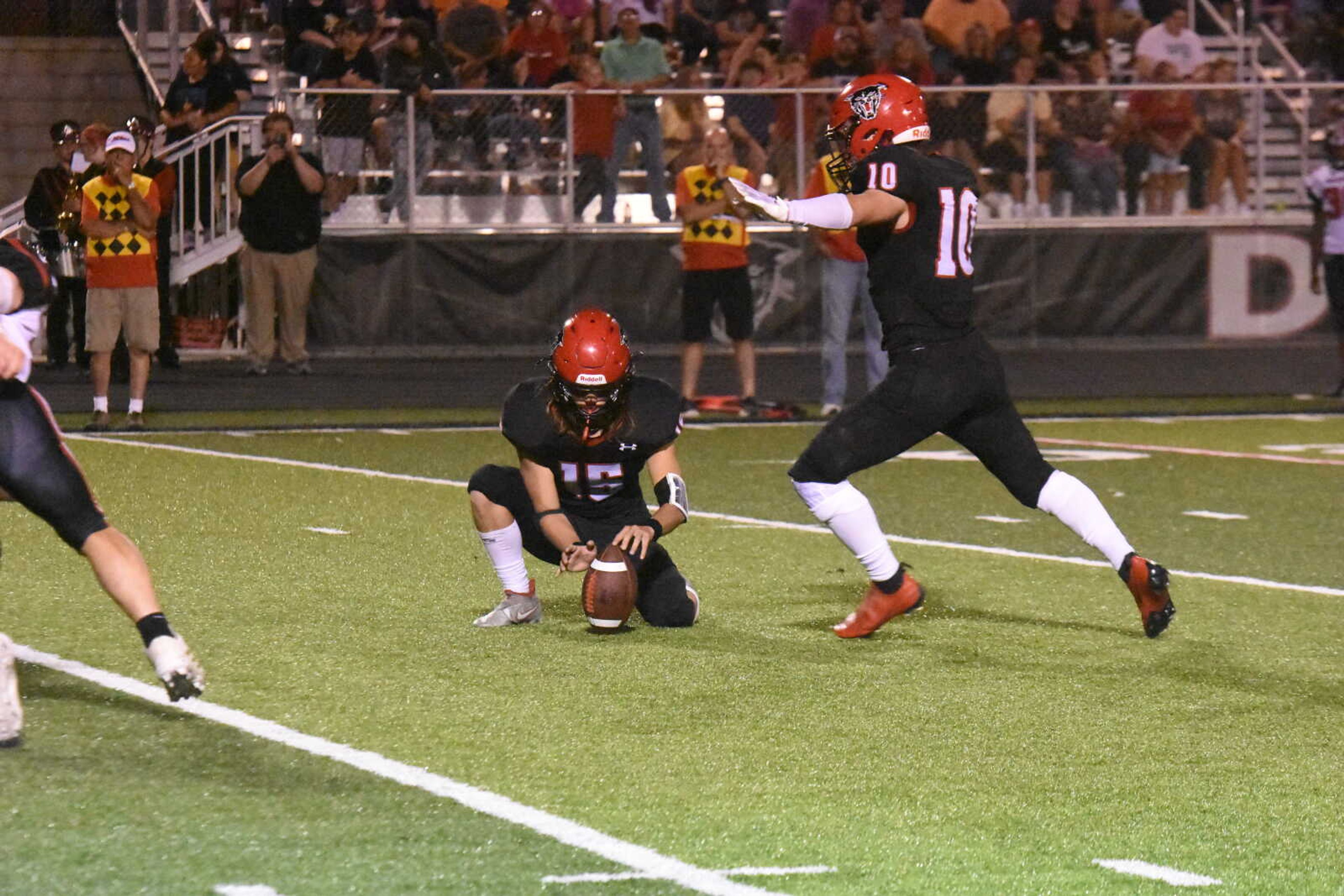 Dexter's Levi Dement (10) kicks a field goal out of the hold of Rhyder Williams (15).