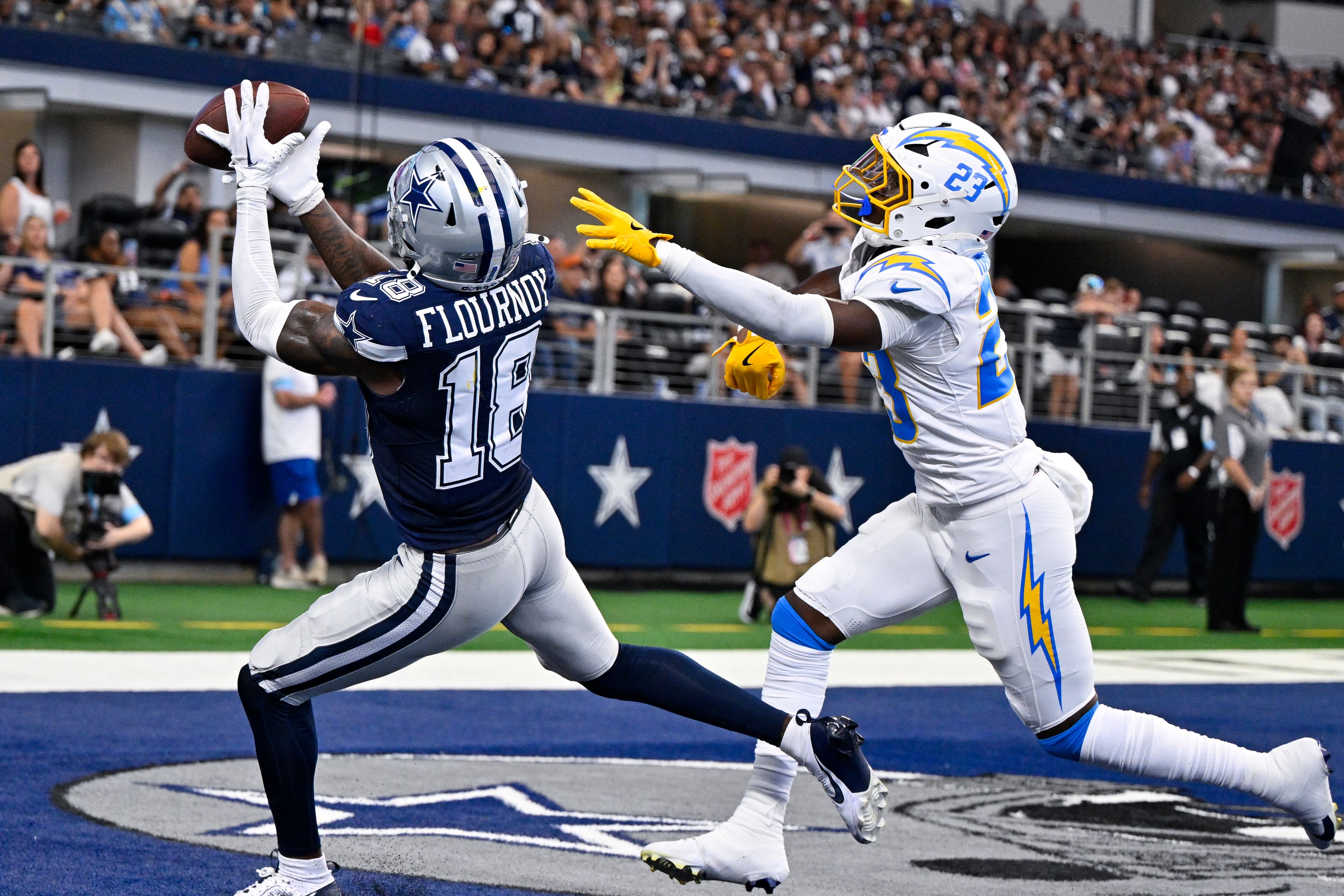 Dallas Cowboys wide receiver Ryan Flournoy (18) catches a touchdown pass over Los Angeles Chargers cornerback Matt Hankins (23) during a preseason NFL football game, Saturday, Aug. 24, 2024, in Arlington, Texas.