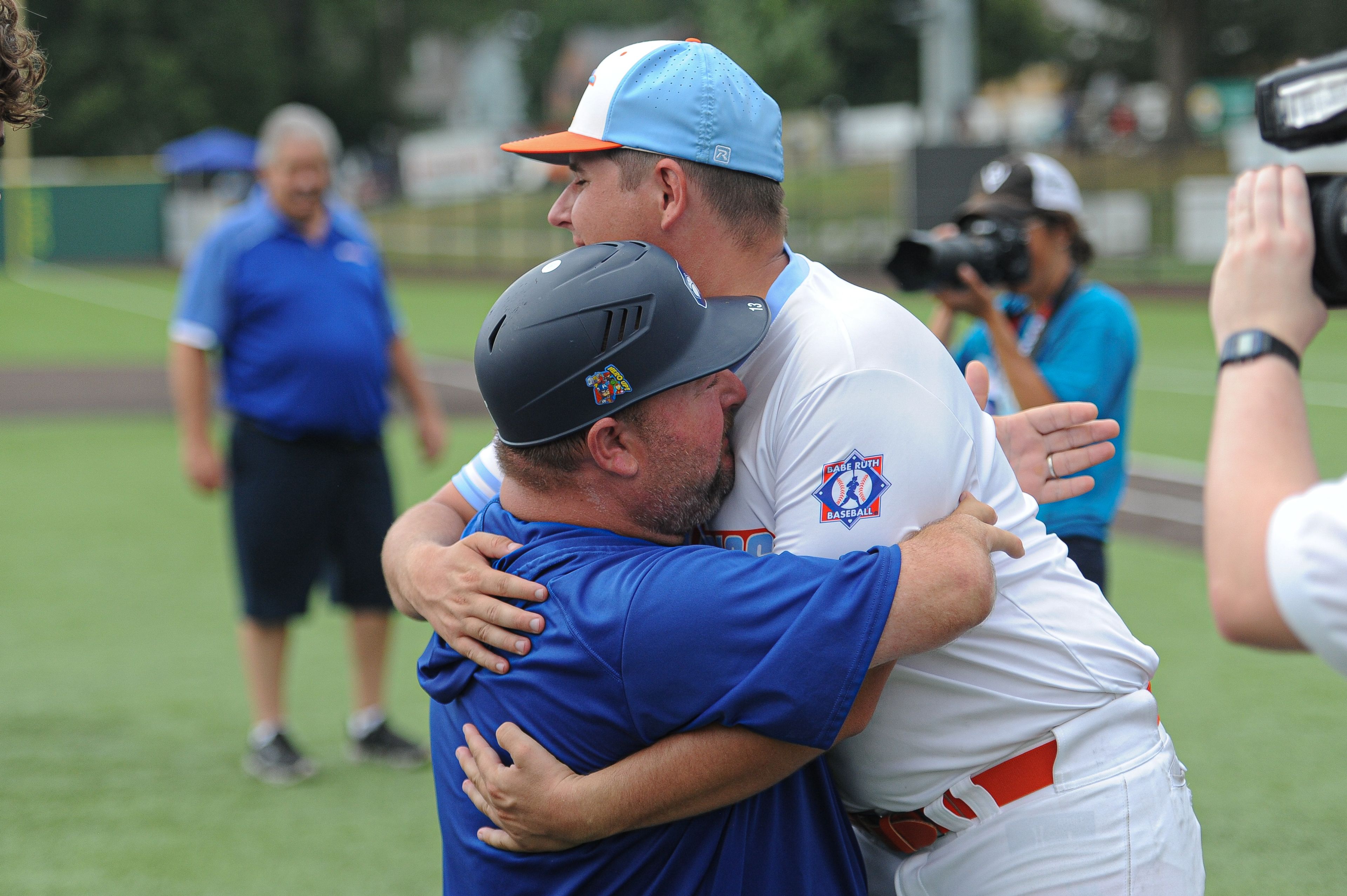 Charleston coach Michael Minner (left) and Southeast coach Dustin Schwartz (right) embrace following the August 15, 2024 Babe Ruth World Series third-place game between the Charleston Fighting Squirrels and the Southeast Tropics at Capaha Field in Cape Girardeau, Mo. Southeast defeated Charleston, 11-2 in five innings.