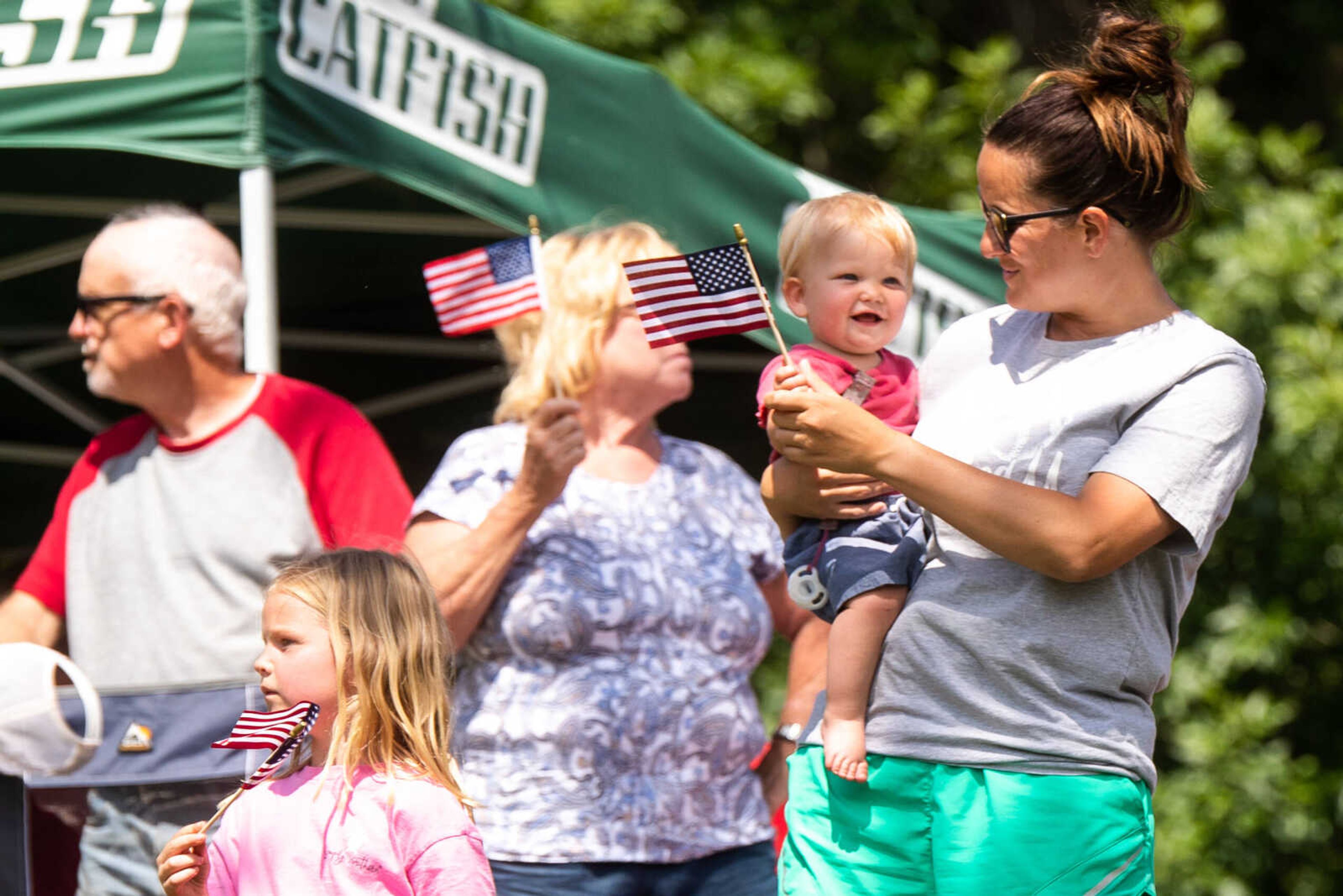 Amber Beard waves a miniature American flag with daughters Halle and Delaney Beard on Wednesday, June 14 at Capaha Field.