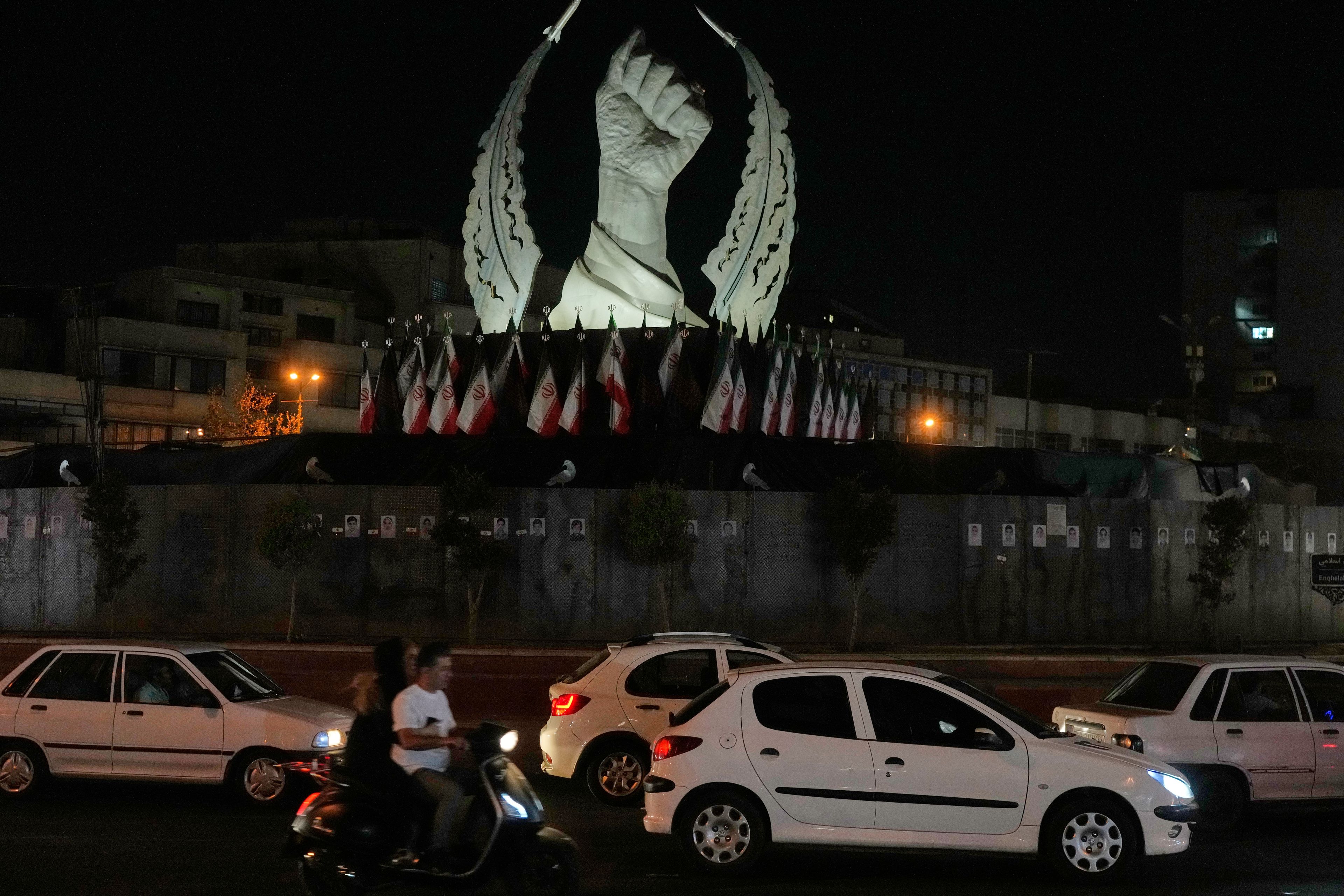 Vehicles drive past a monument depicting the clenched fist of the late Iranian Supreme Leader Ayatollah Ali Khamenei, who was killed in the U.S. and Israel strike on Feb. 28, in Islamic Revolution Square in Tehran, Sunday, July 19, 2026. (AP Photo/Vahid Salemi)