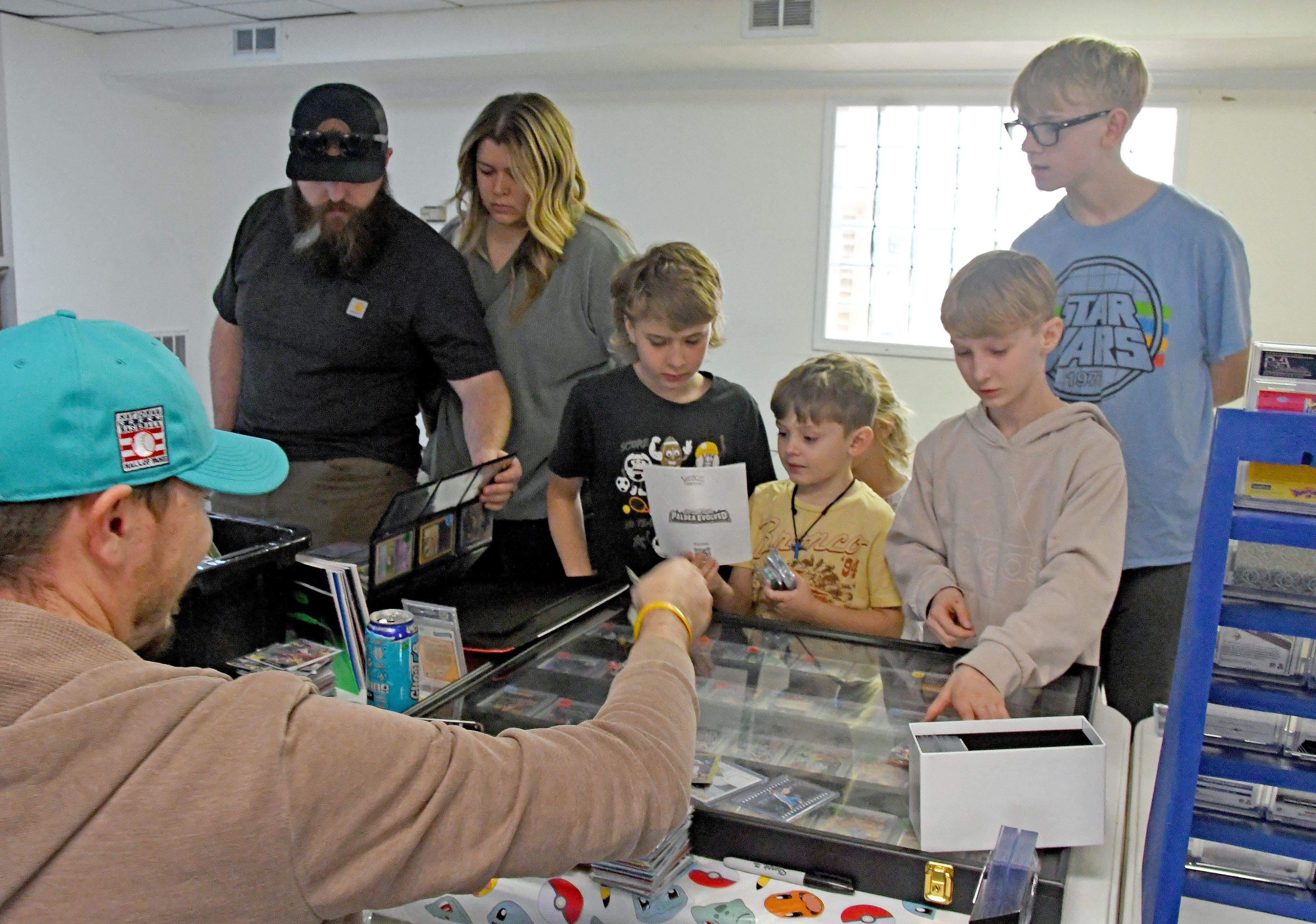 Nick Denzel (seated left) shows some of his sports memorabilia to visitors at the Cards and Collectibles Show on March 21 at the New Madrid Community Building. The event brought about 200 people out to visit with vendors and purchase items. According to the members of the Rotary Club, which sponsored the event, another Cards and Collectibles Show is being planned for next fall.