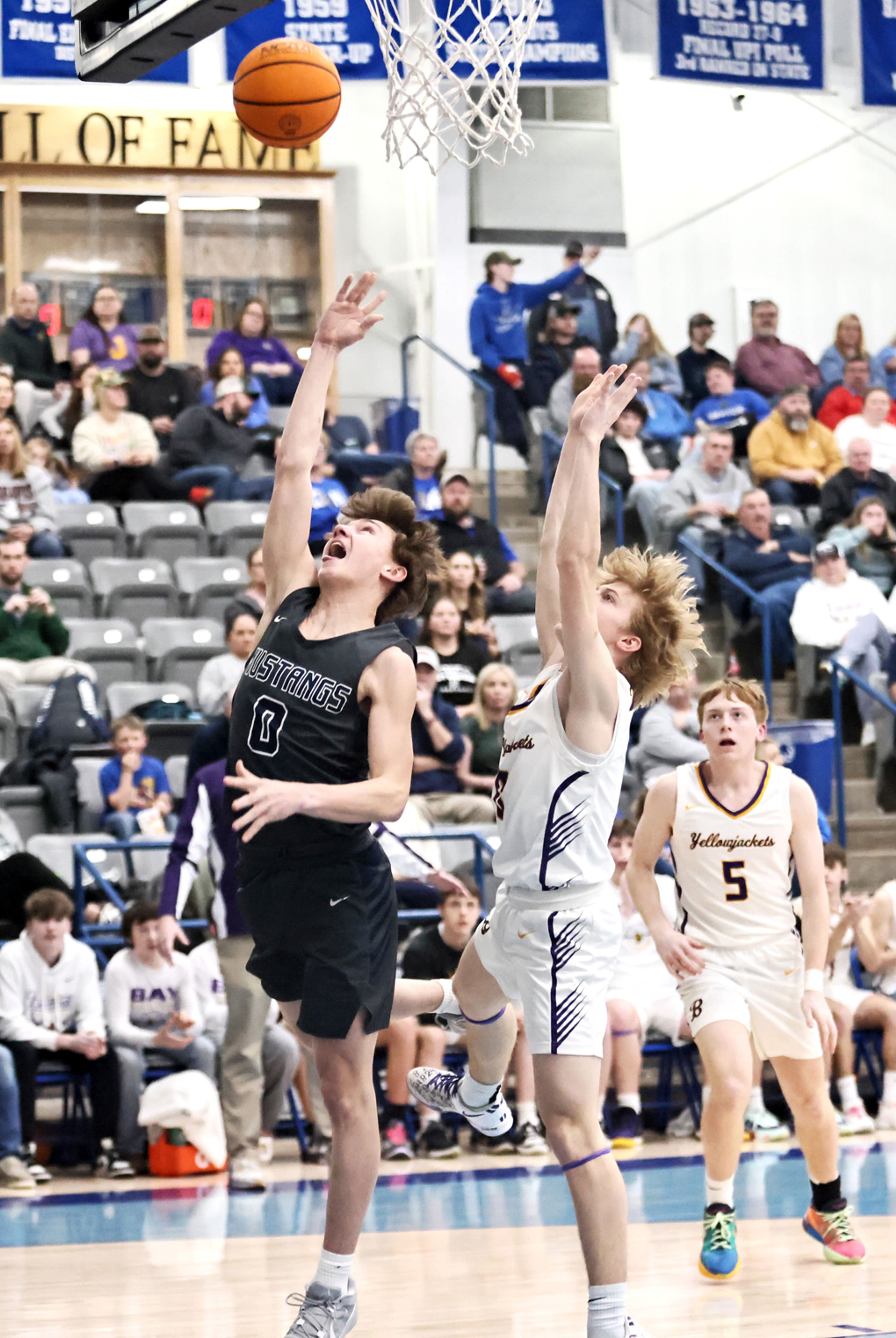 BIC’s Zander Jackson goes in two points as Bay’s Cade Spencer defends during district tournament action in Rector. (Photo by Cosmo Cossey)