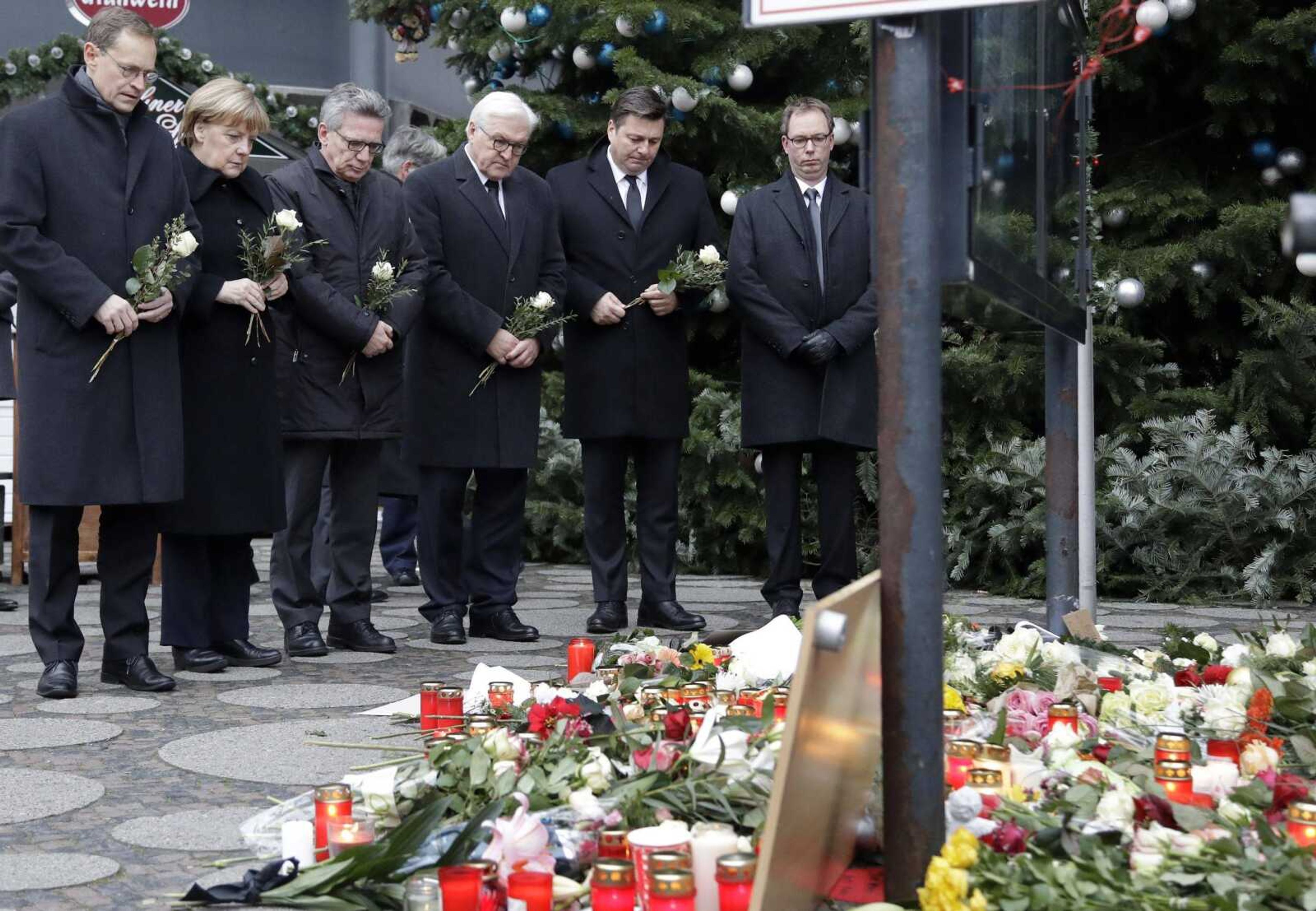 German officials, including Chancellor Angela Merkel, attend a flower ceremony Tuesday at the Kaiser-Wilhelm Memorial Church in Berlin, the day after a truck ran into a crowded Christmas market and killed several people.