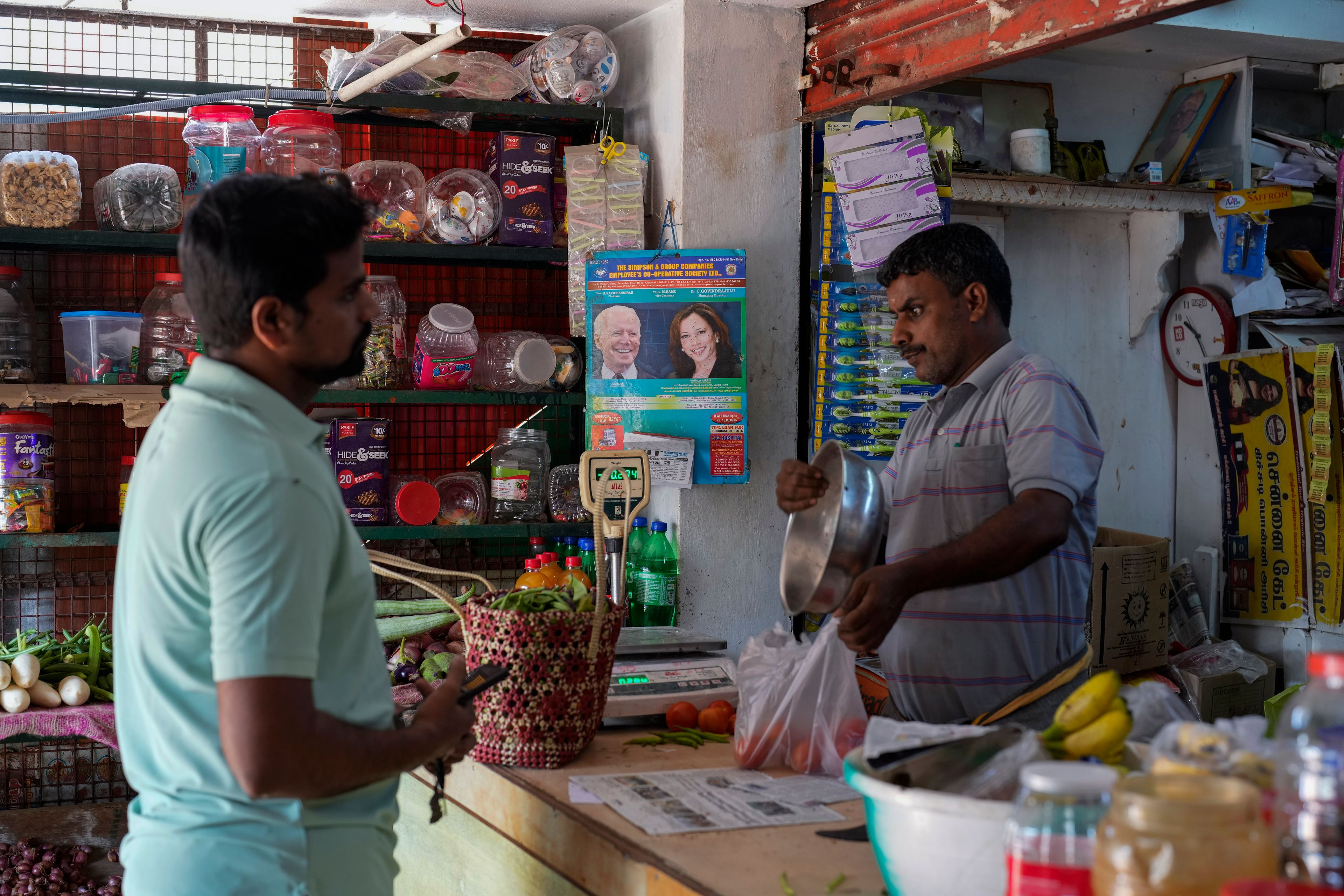 Manikandan Ganesan, right, a local shopkeeper, packs vegetables for a customer at his grocery store outside Sri Dharmasastha Hindu temple in Thulasendrapuram, the ancestral village of Democratic presidential nominee Vice President Kamala Harris, in Tamil Nadu state, India, Monday, Nov. 4, 2024. (AP Photo/Aijaz Rahi)