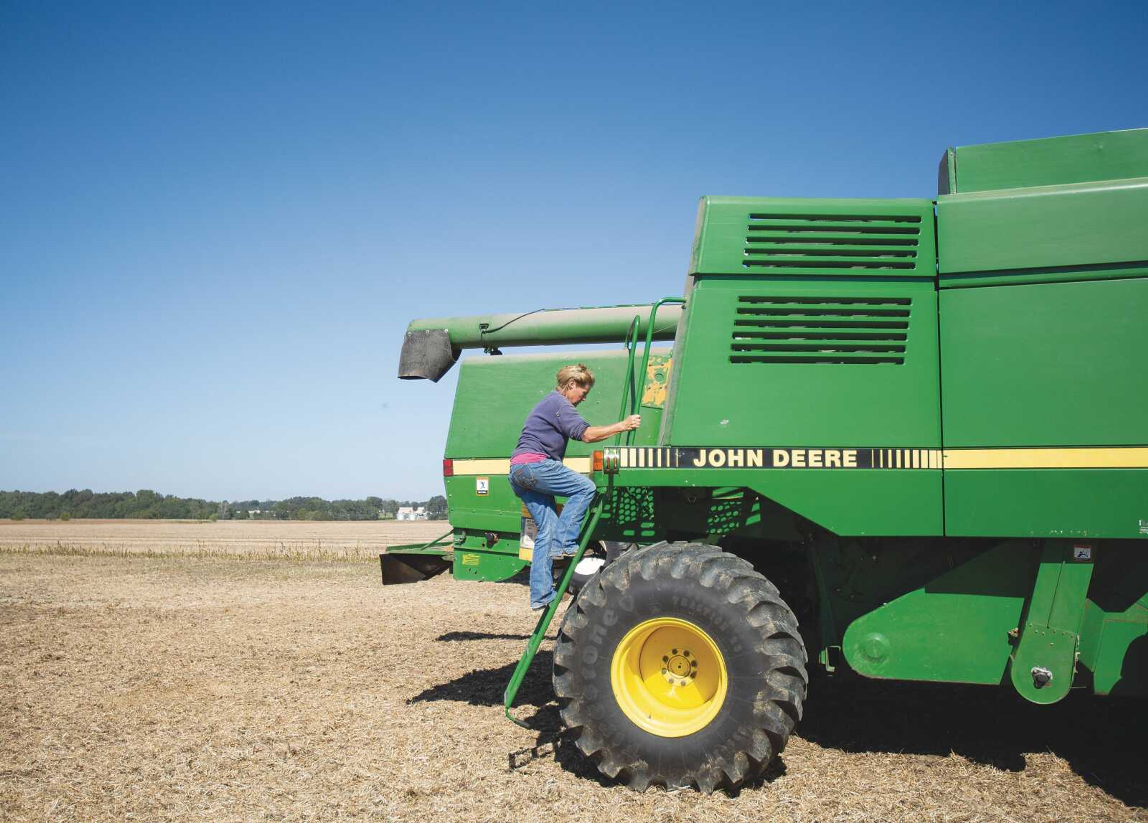 Susan Jahn climbs up to the hopper of a combine, preparing it for a day of harvesting soybeans in one of many fields cultivated by Jahn Farms.
