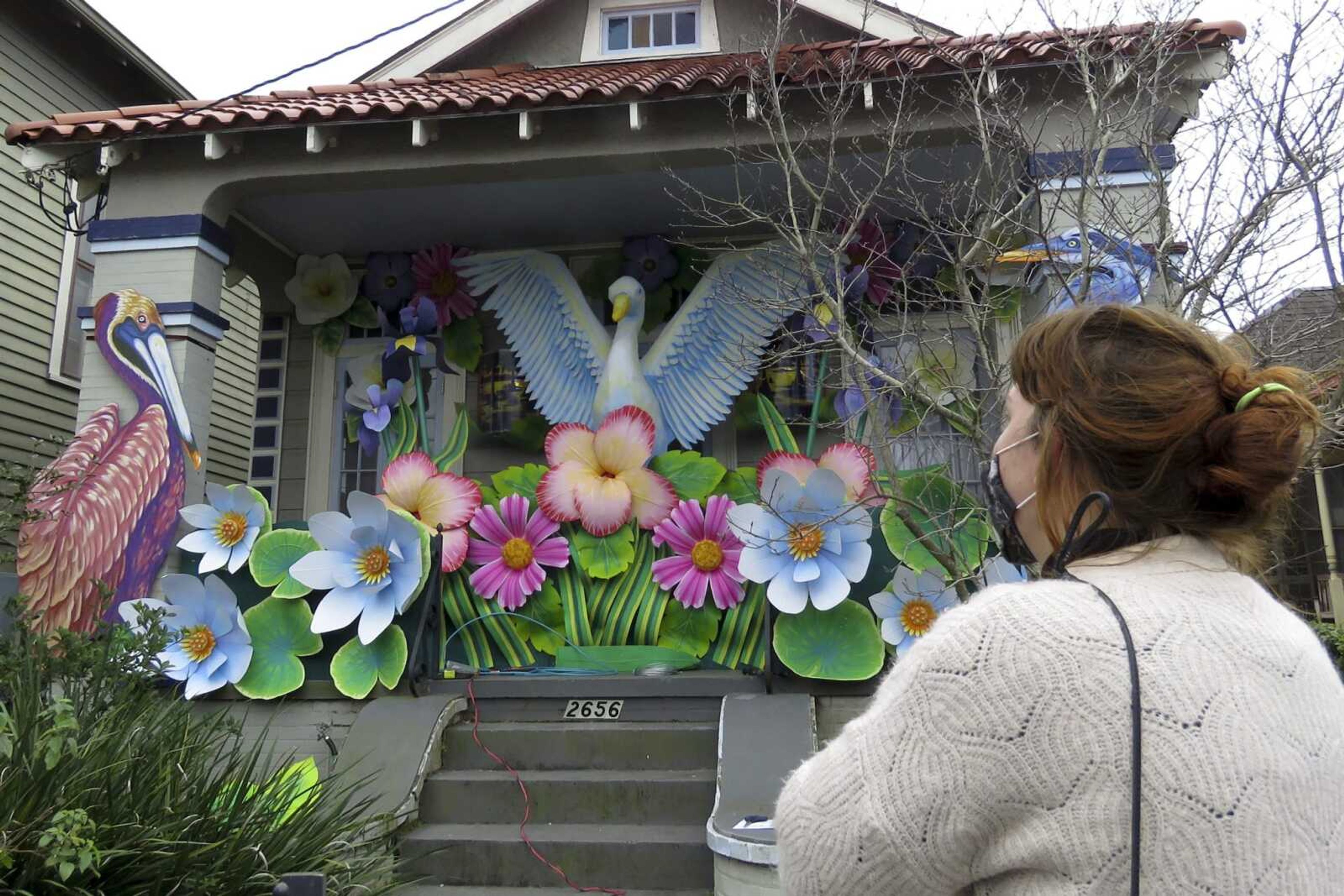 Designer, Caroline Thomas looks at a house decorated like a parade float in New Orleans on Friday, Jan. 8, 2021. All around the city, thousands of houses are being decorated as floats because the coronavirus pandemic has canceled parades that usually take place on Mardi Gras. (AP Photo/Janet McConnaughey)